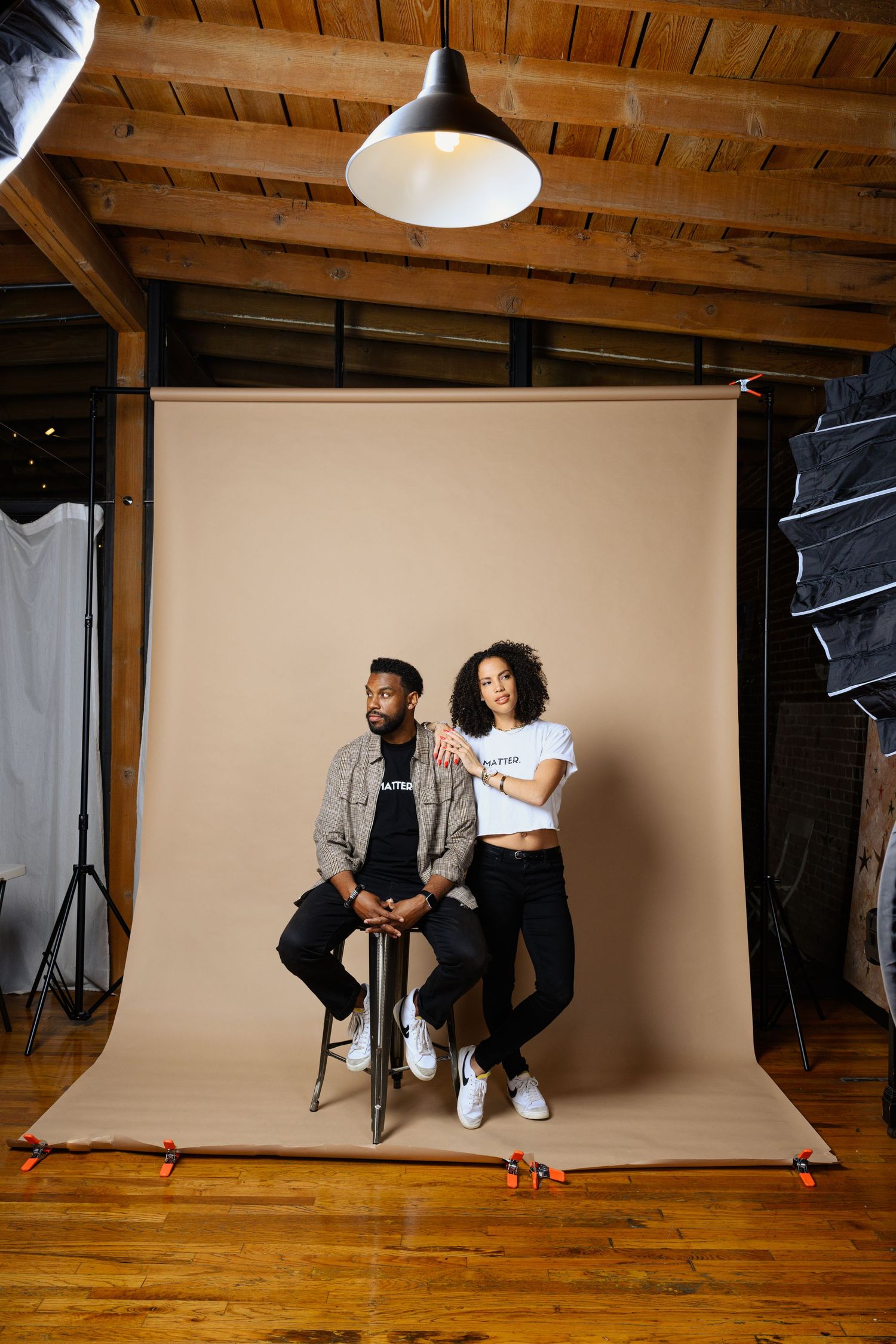 Professional photo studio setup with white backdrop and wooden floor showing behind-the-scenes photography session.