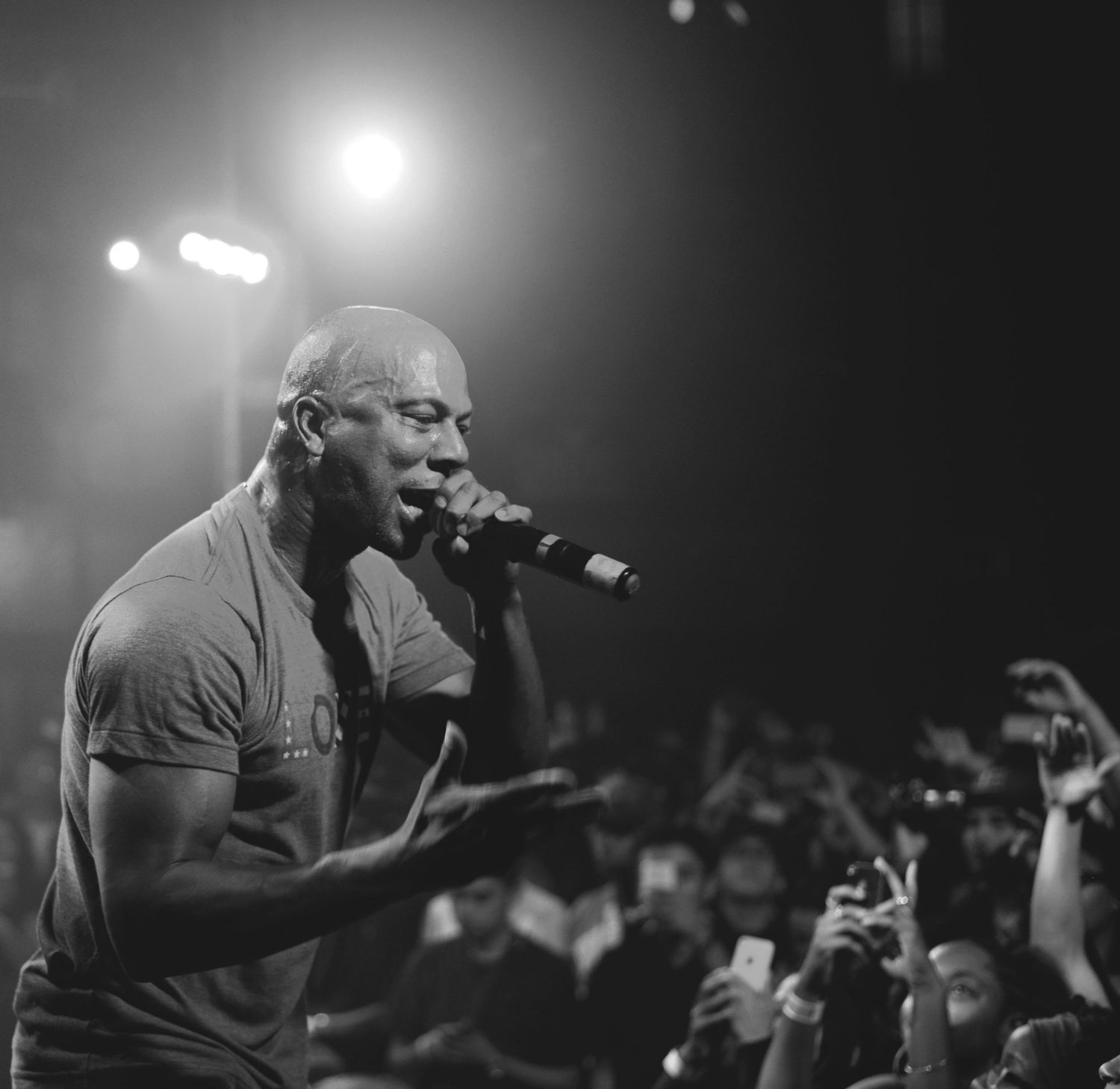 Concert performer singing passionately in black and white with dramatic stage lighting.