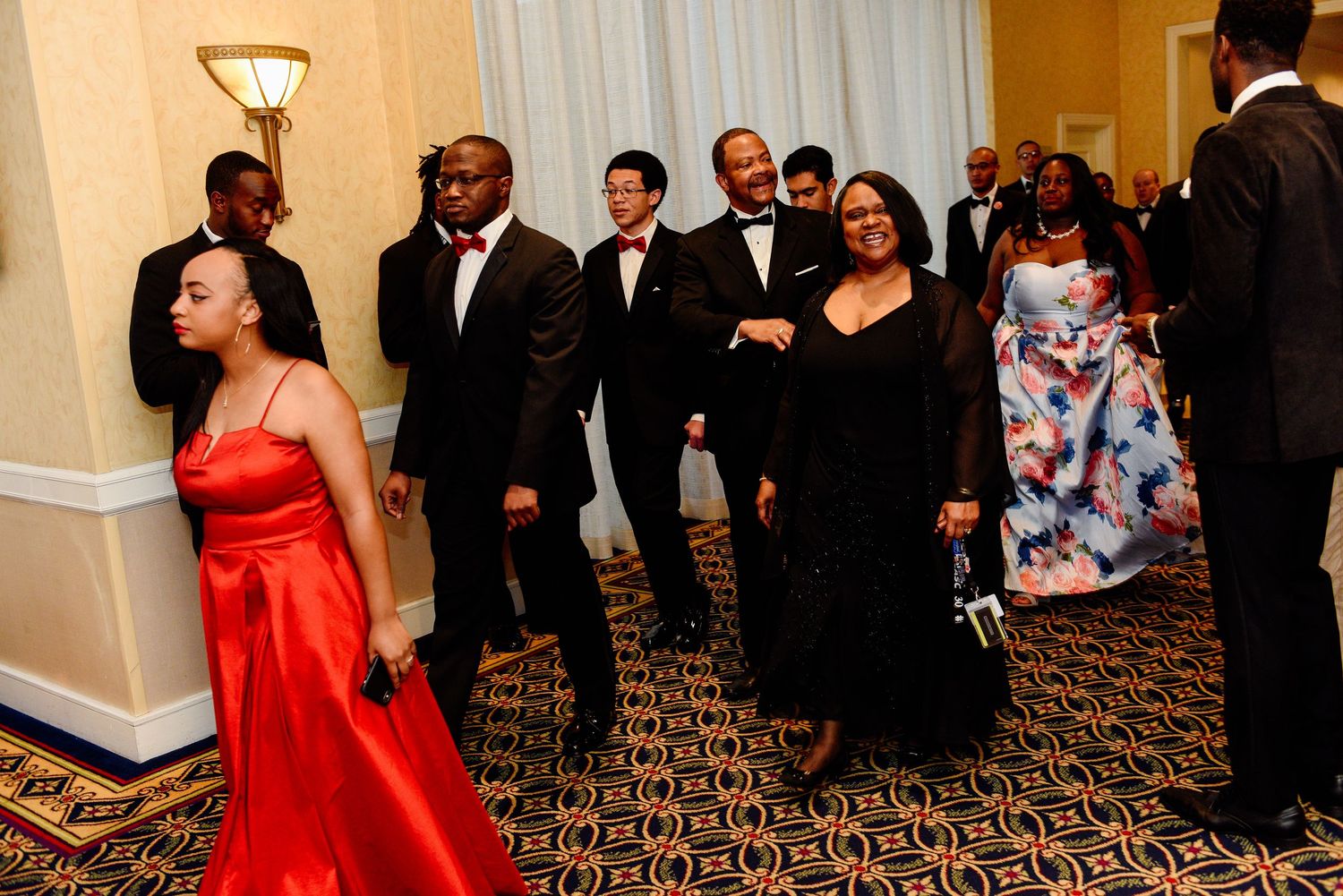 Formal event gathering in hotel ballroom with guests in evening wear.