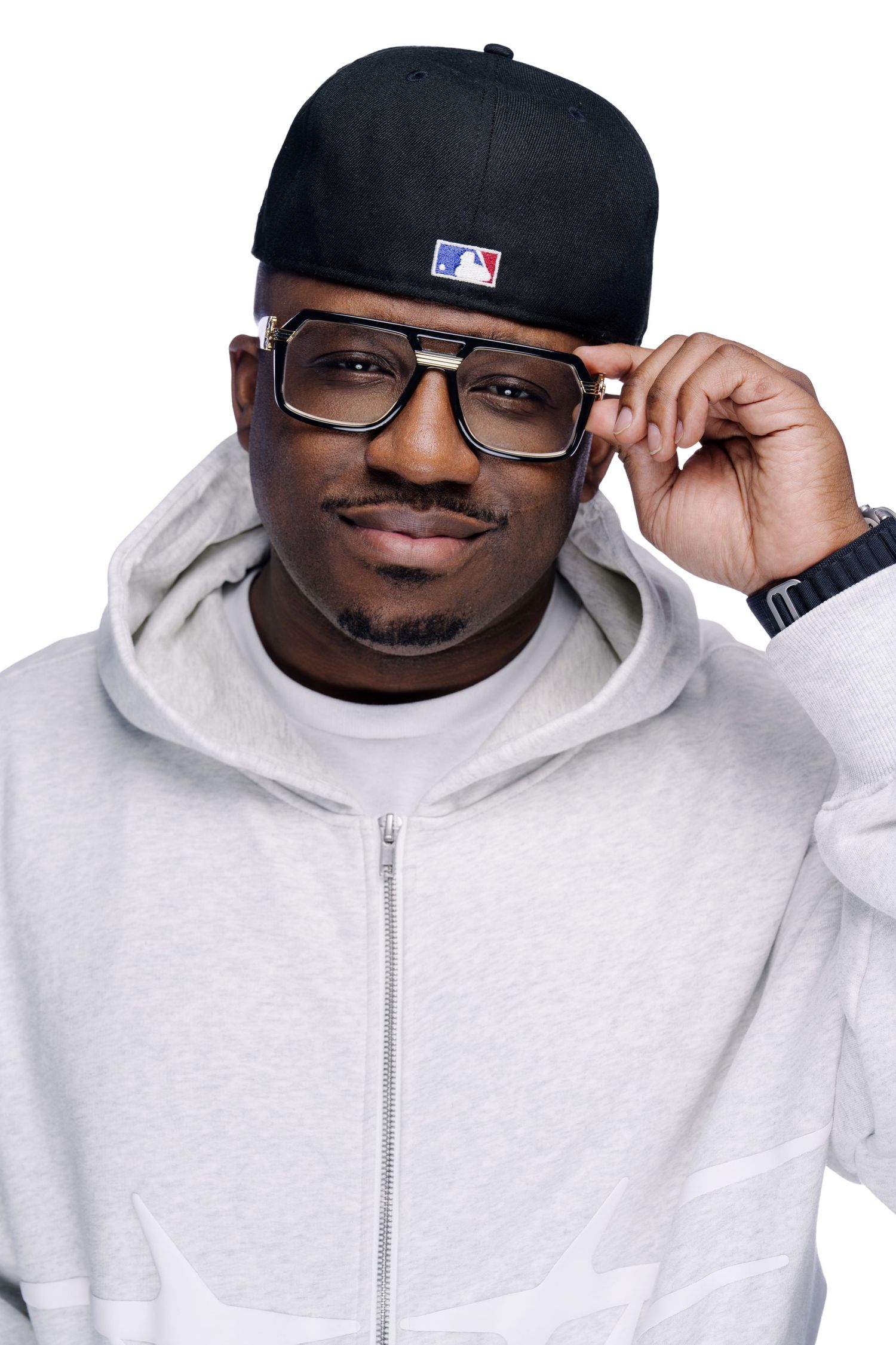 Casual portraits of a person in glasses and white hoodie adjusting their MLB cap.