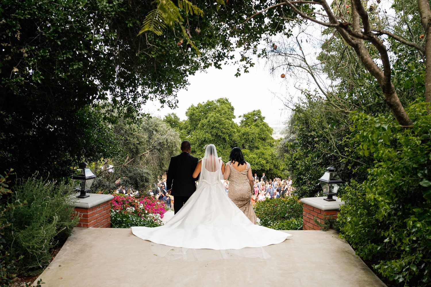 Panoramic wedding scene with white dress flowing in garden setting.