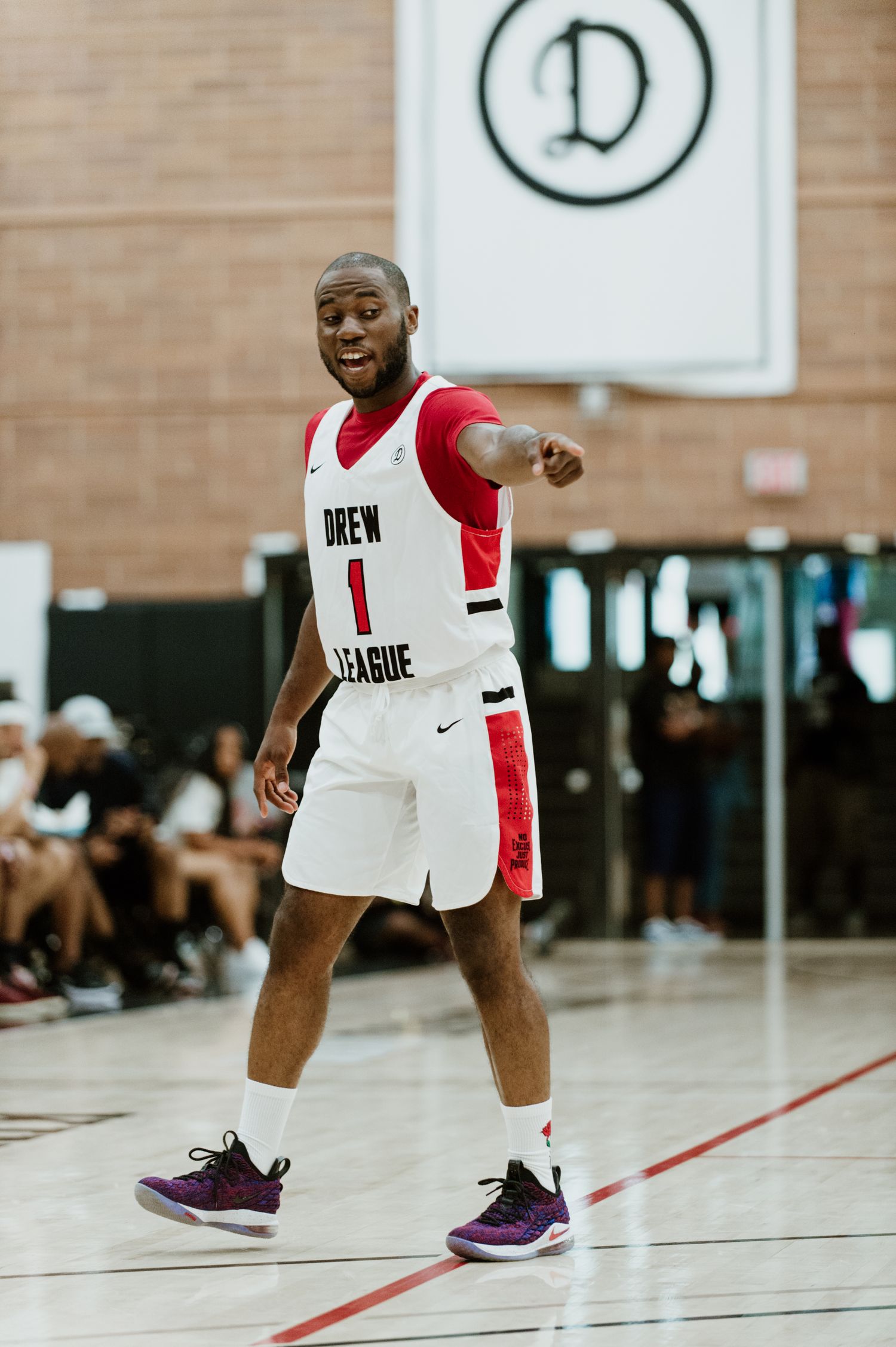 Basketball player in white and red uniform gestures during indoor game.