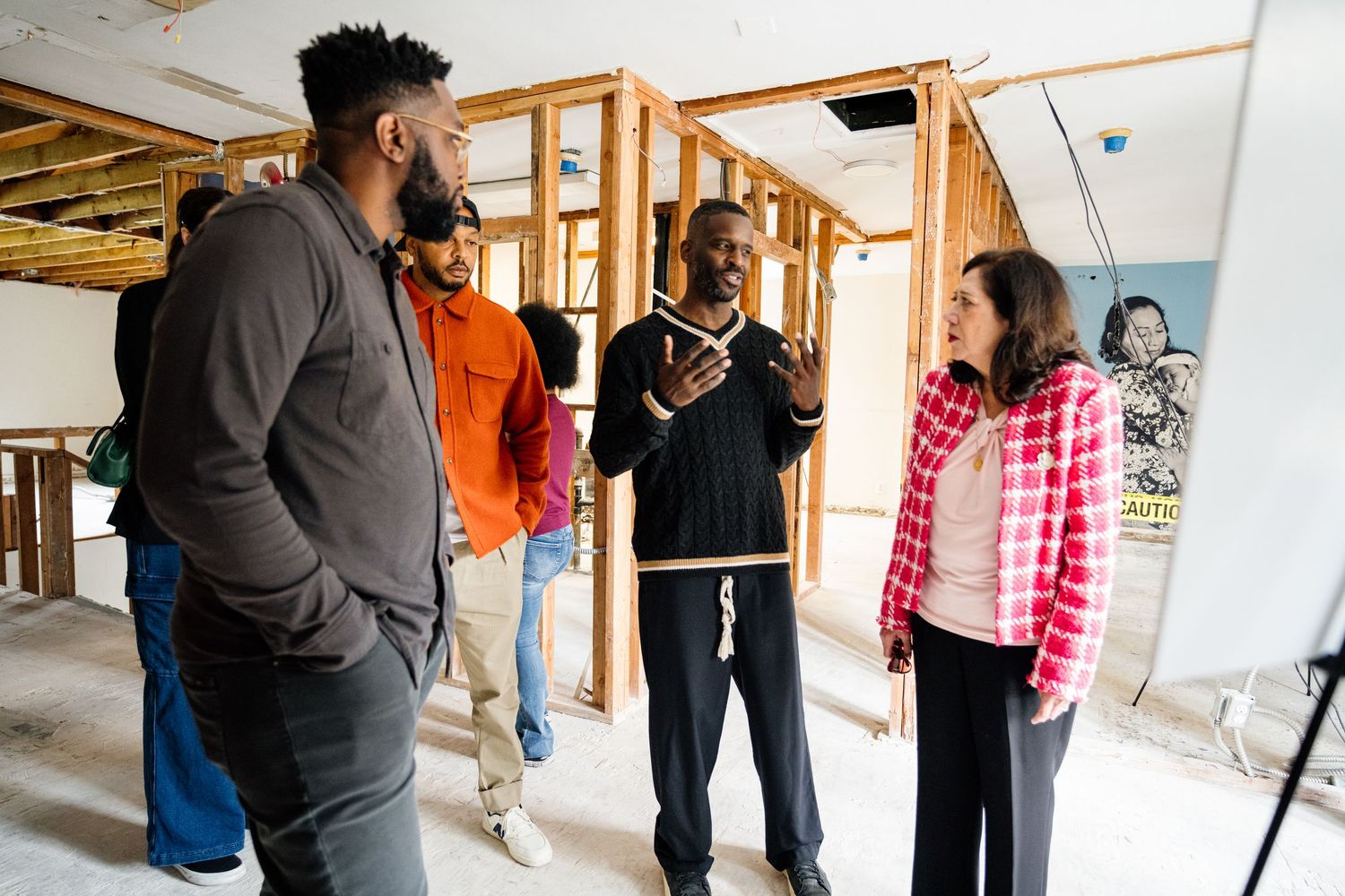 Group gathering in building under renovation with exposed wooden framing.