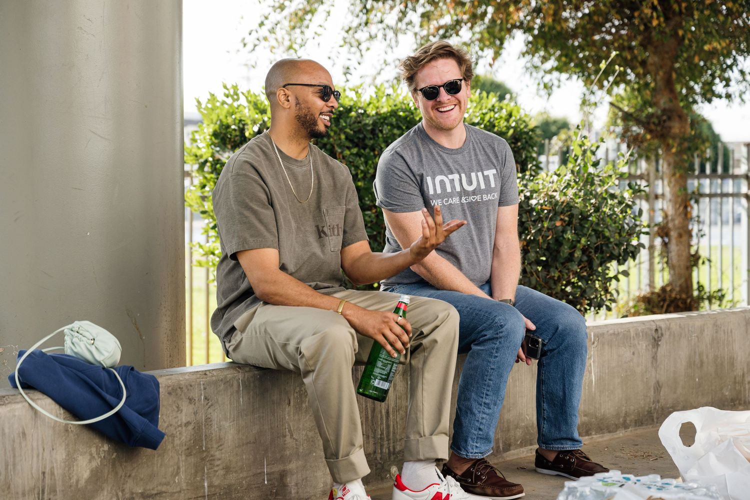 People sitting and chatting on a concrete ledge at an outdoor event.