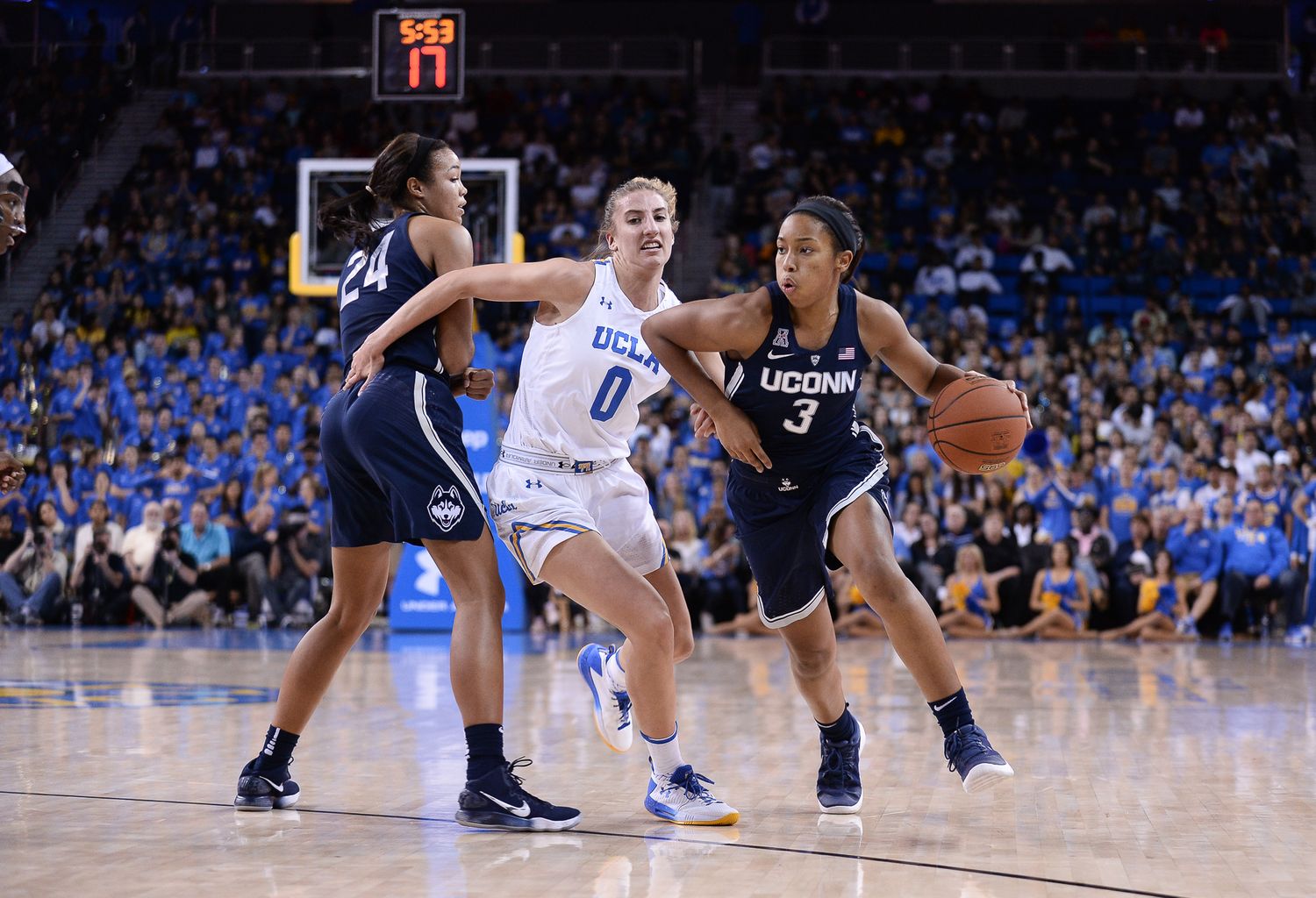 Women's college basketball players compete for position during intense game action.