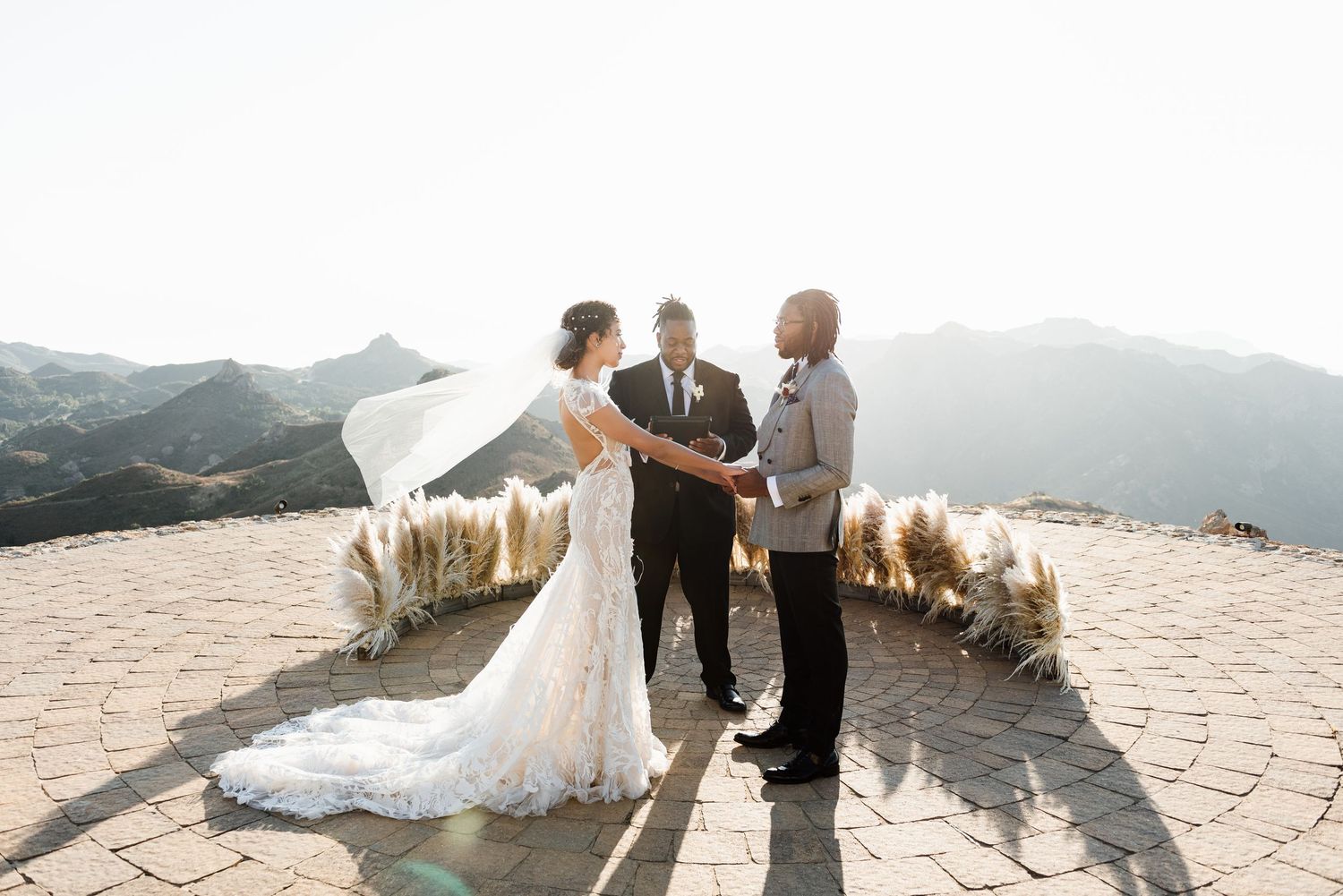 Wedding ceremony setup on a mountaintop with panoramic views and floral arrangements.