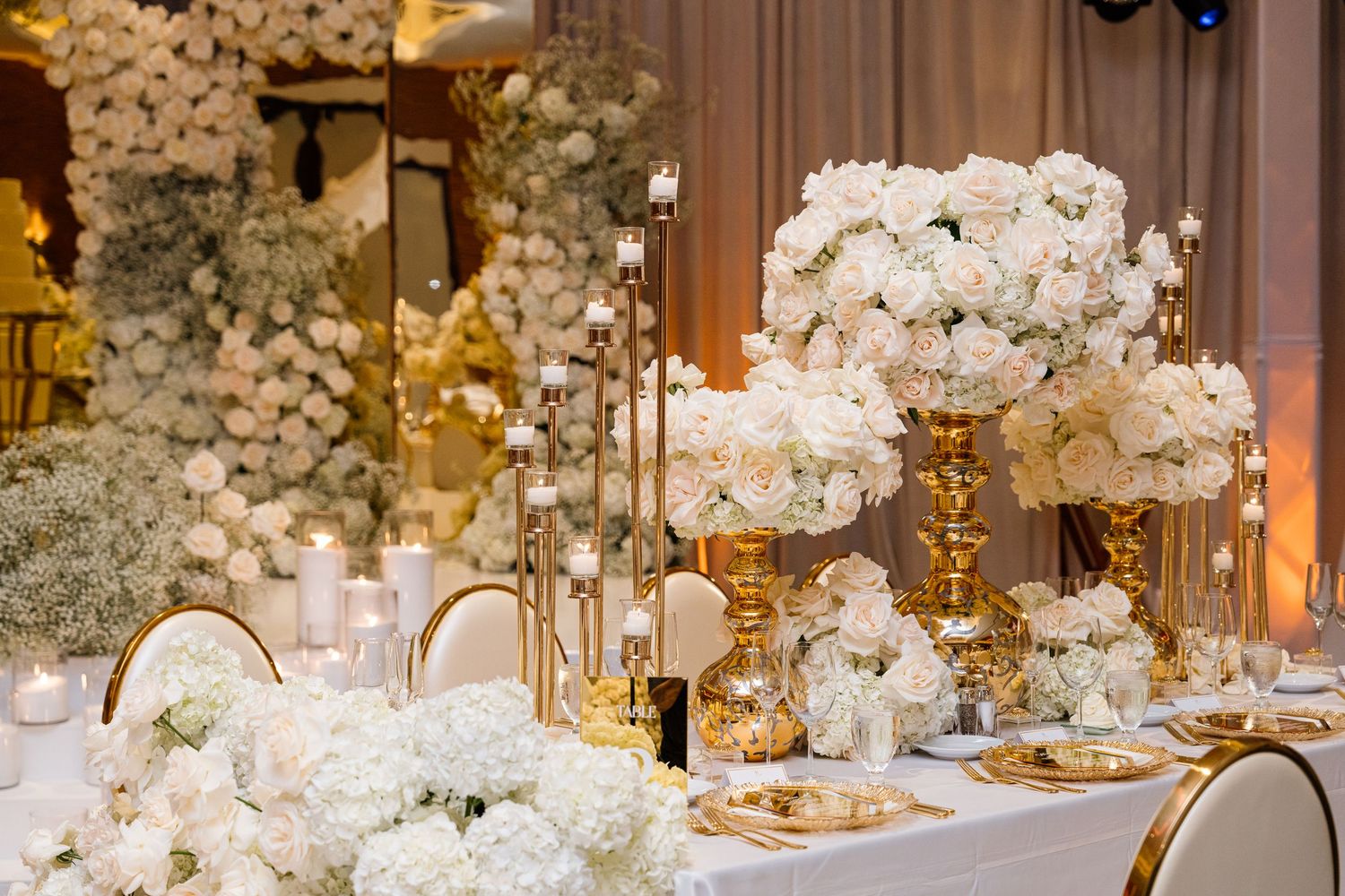 Luxurious wedding reception tables decorated with white floral centerpieces and crystal candelabras.