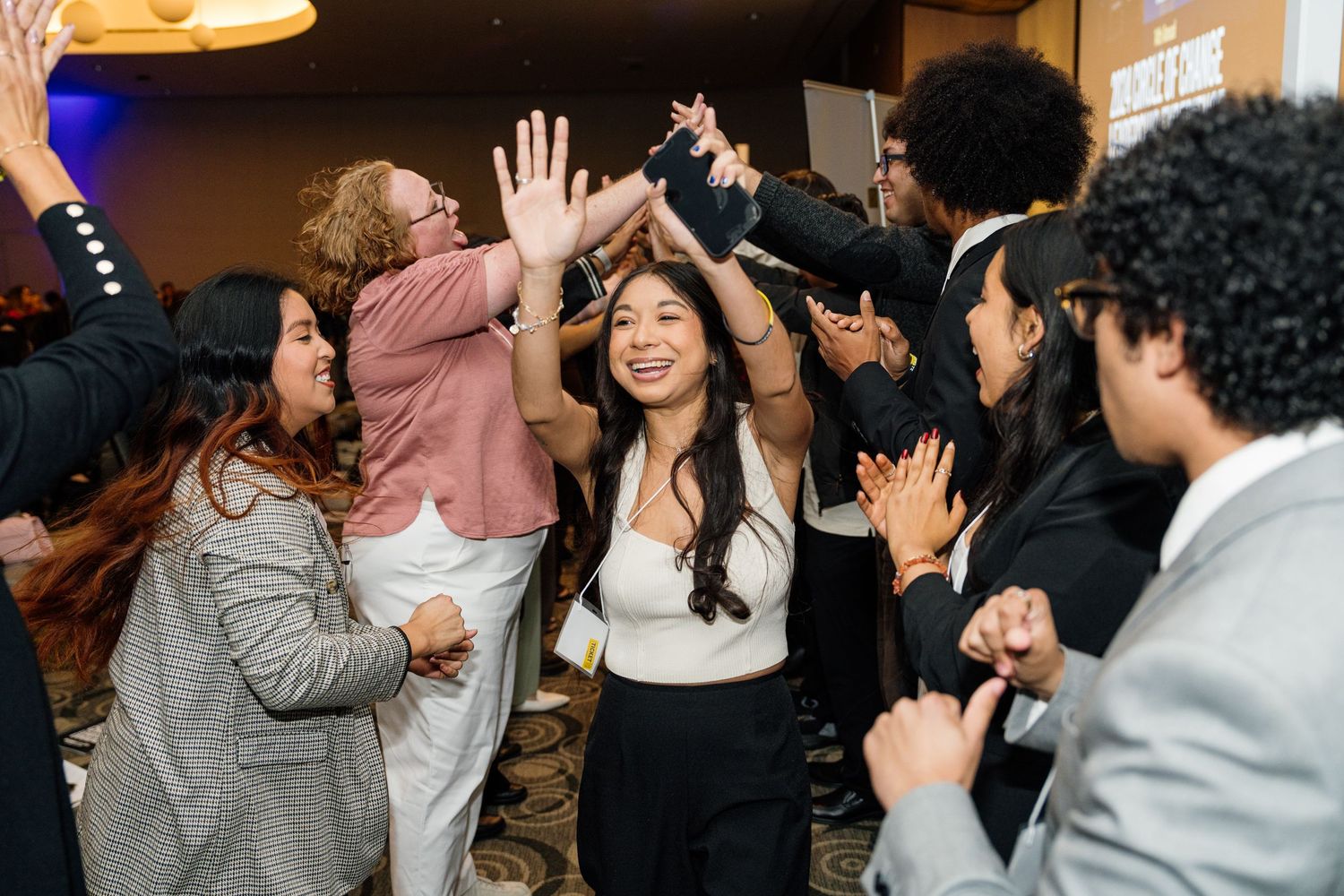 Enthusiastic crowd of people raising their hands and participating in an event.