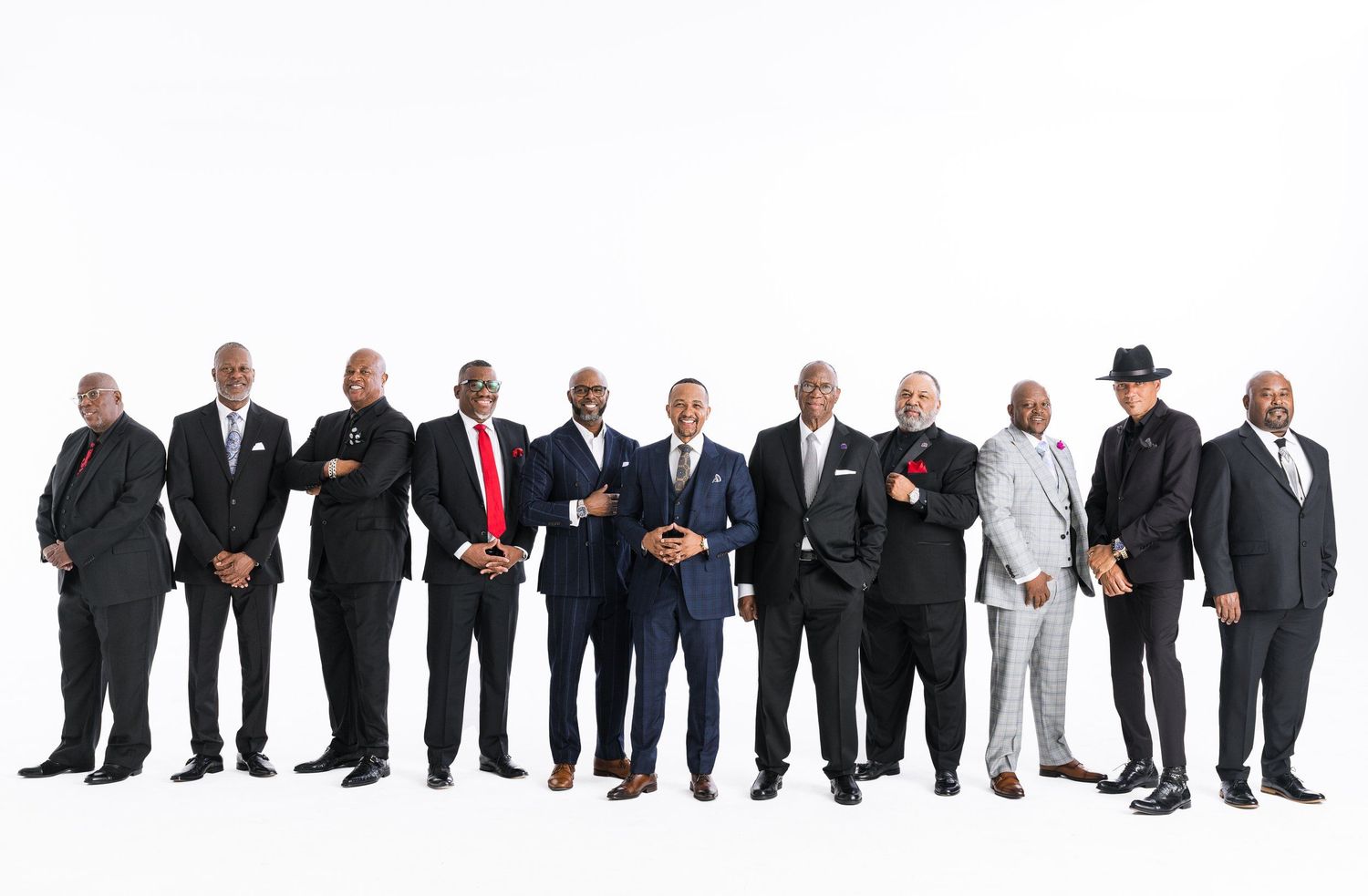 Professional business people standing in a row wearing suits and formal attire against white background.