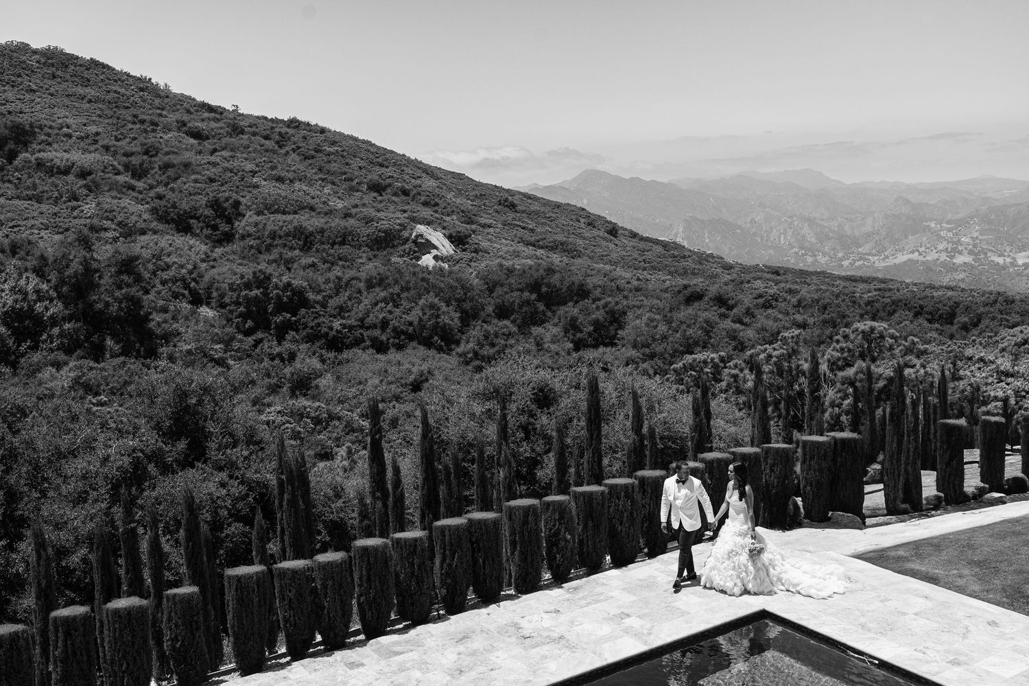 Panoramic mountain landscape with wooden fence posts stretching along a scenic hiking trail.
