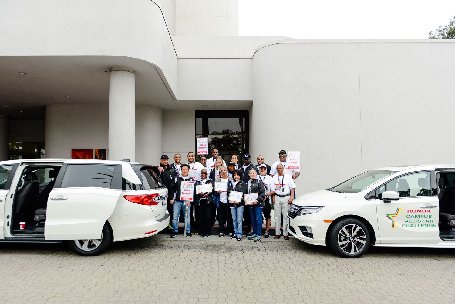 Group of participants standing next to white vehicles at a Honda event.