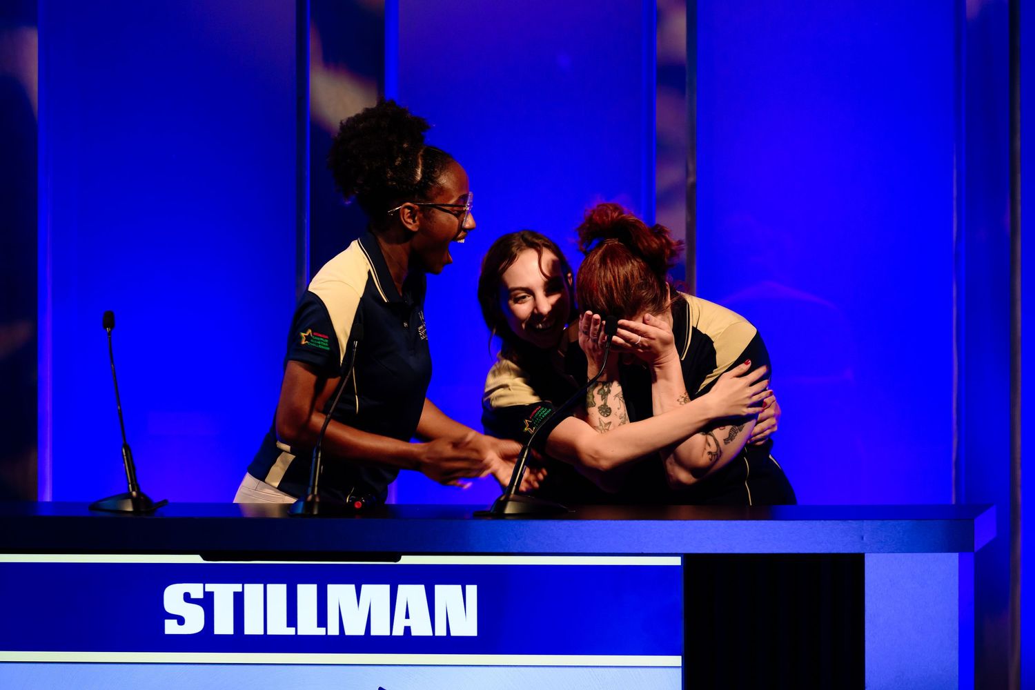 Event participants interacting on stage with blue backdrop and Stillman text.