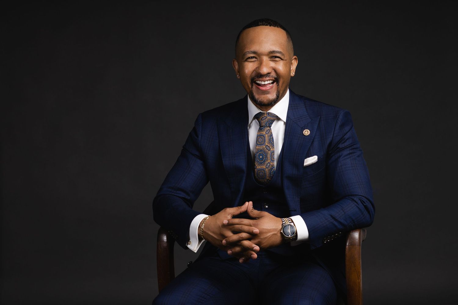 Professional portrait against dark background in formal business attire.