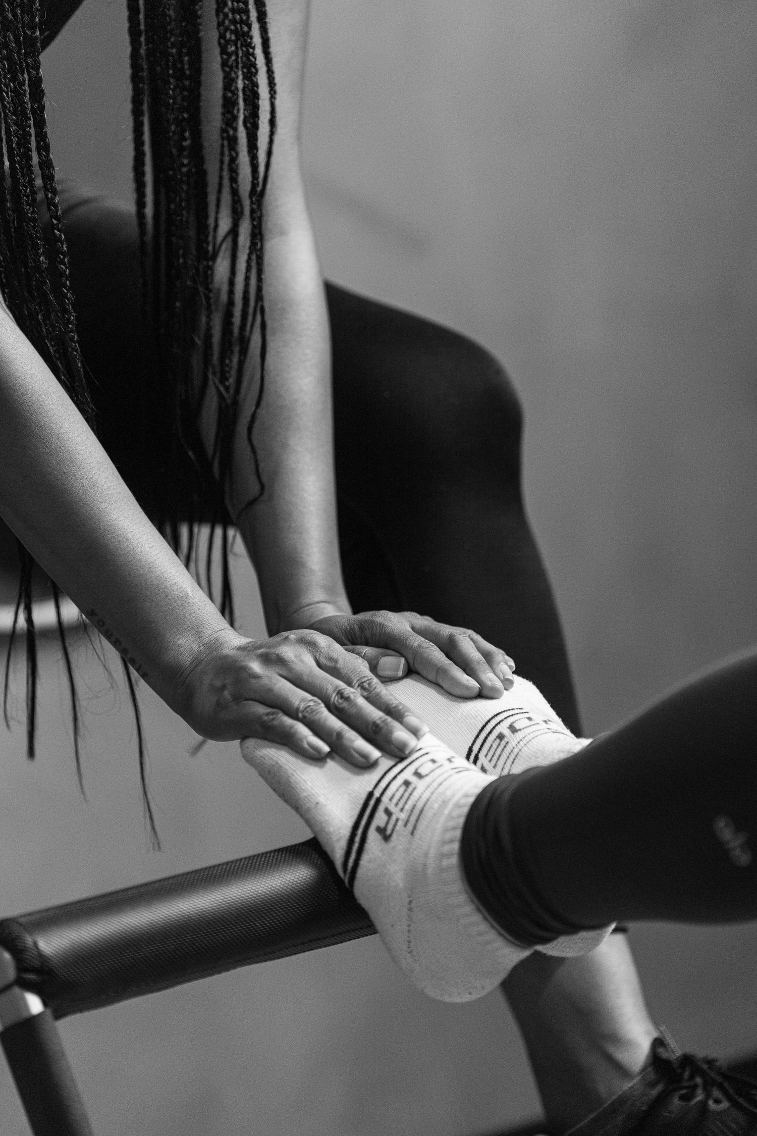 Close-up black and white shot of hands gripping exercise equipment.