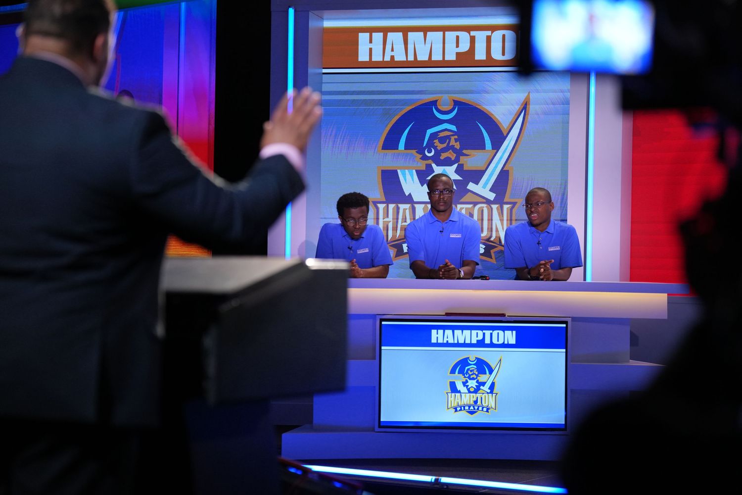 Hampton University team competes on a televised academic quiz show, seated behind a branded desk under studio lights.