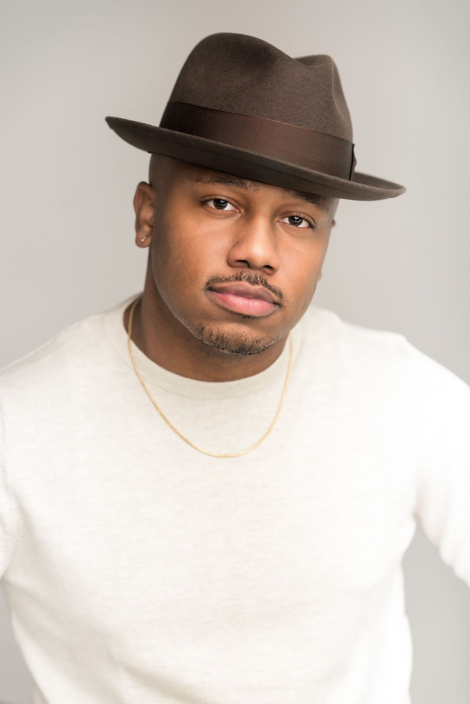 Portrait series showing person in white sweater and brown fedora hat against light background.