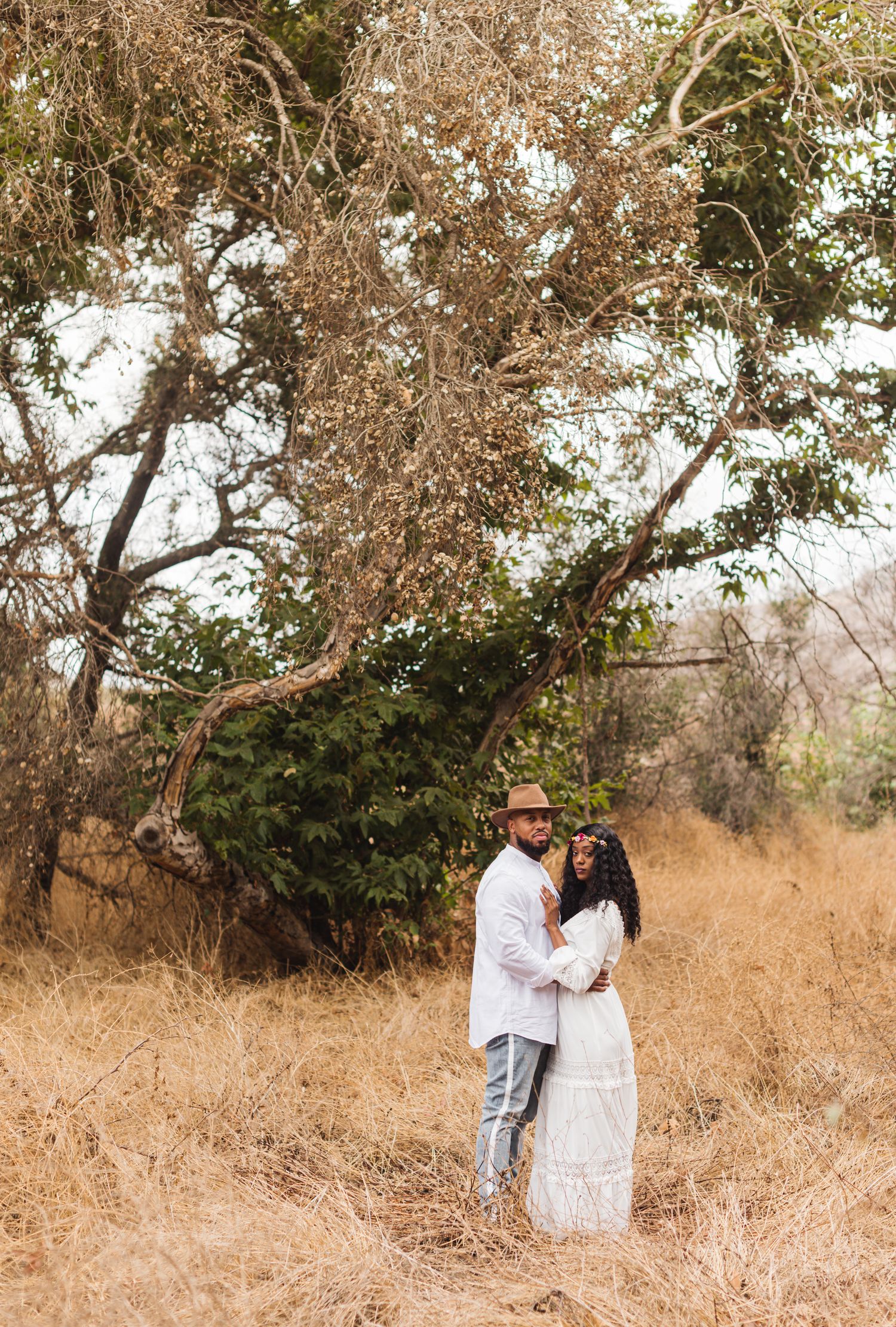 Couple taking romantic photos in golden field with autumn trees.