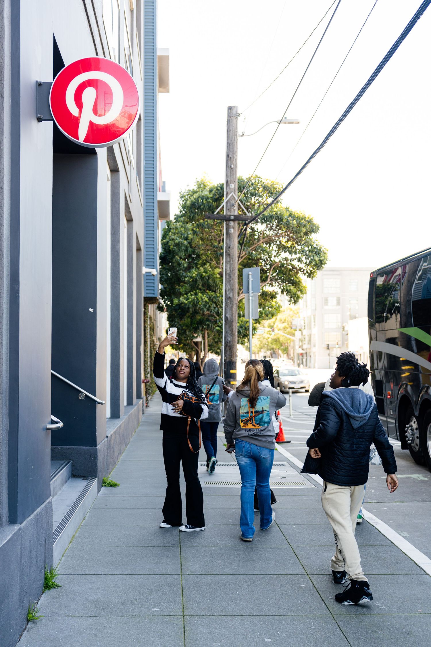 People walking along a modern urban sidewalk with gray pillars and buildings.