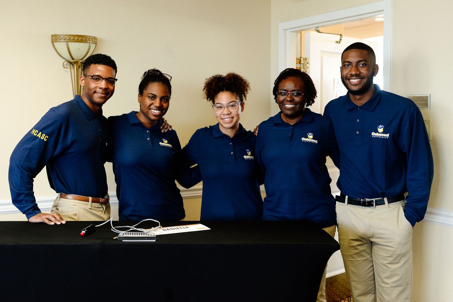 Group wearing matching navy blue uniforms pose together in an office setting.