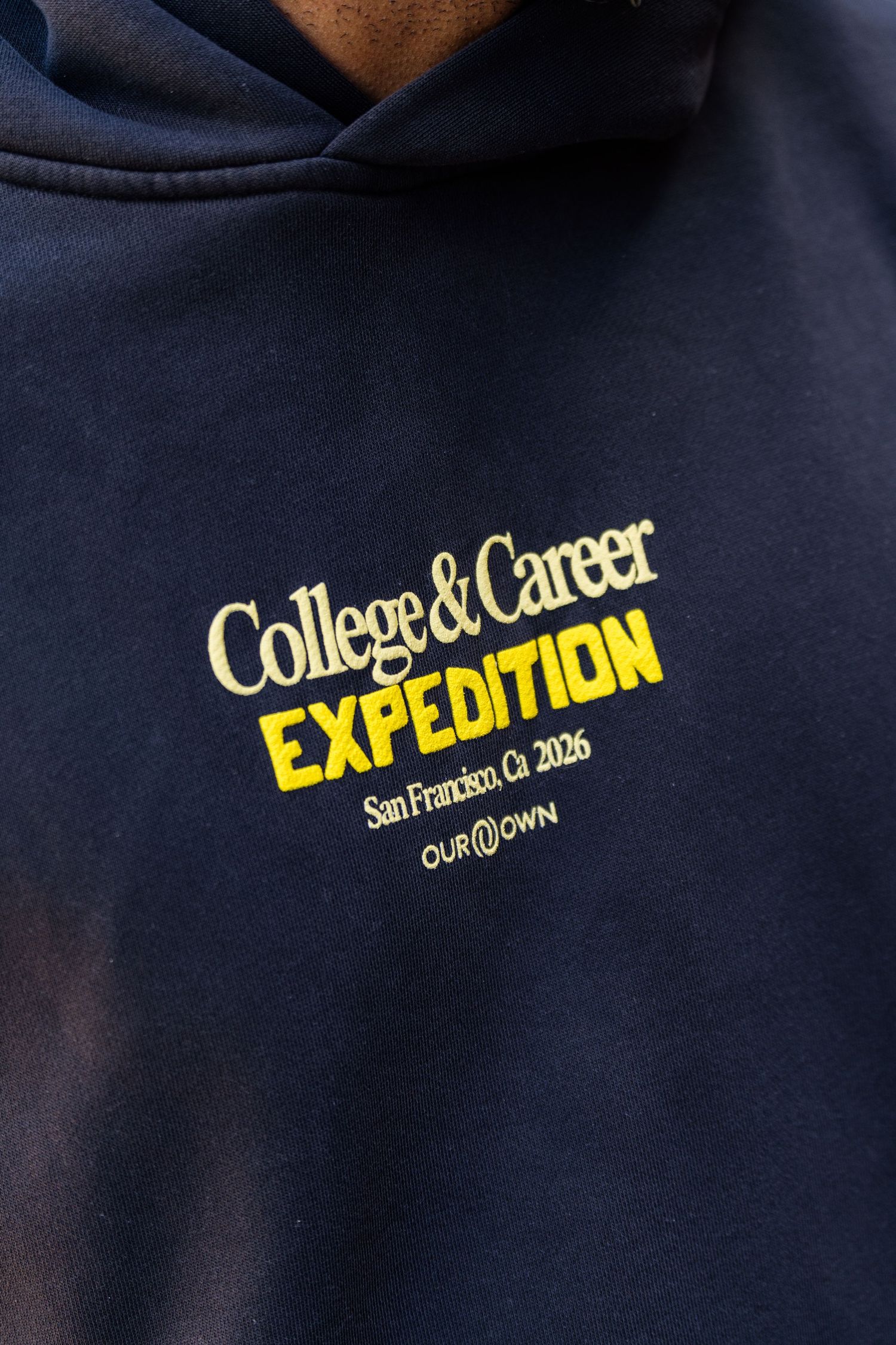 Navy blue hoodie with yellow College & Career Expedition San Francisco CA 2026 Our Own embroidered graphic.