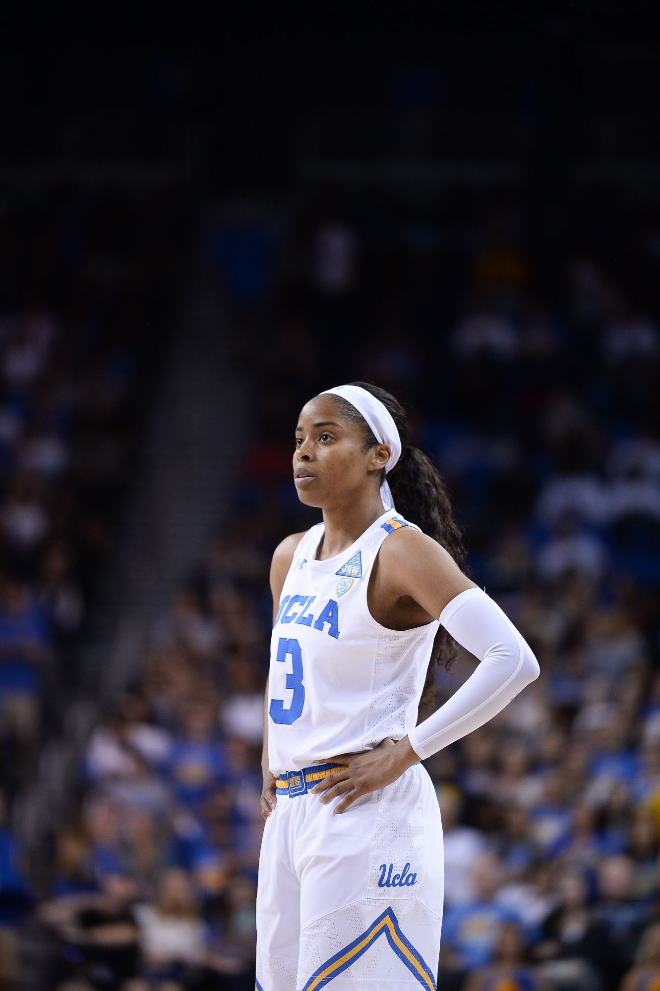 Basketball player in white UCLA uniform stands on court during game.