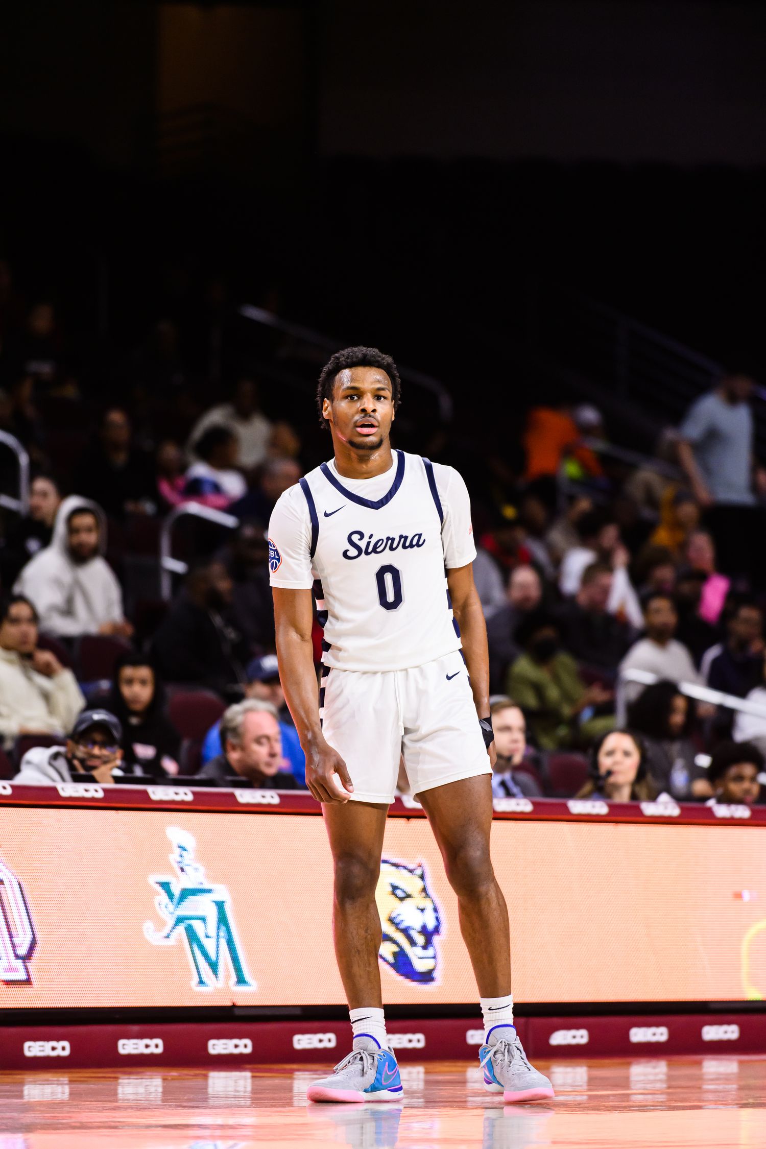 Basketball players in white jerseys sitting on a bench during a game.