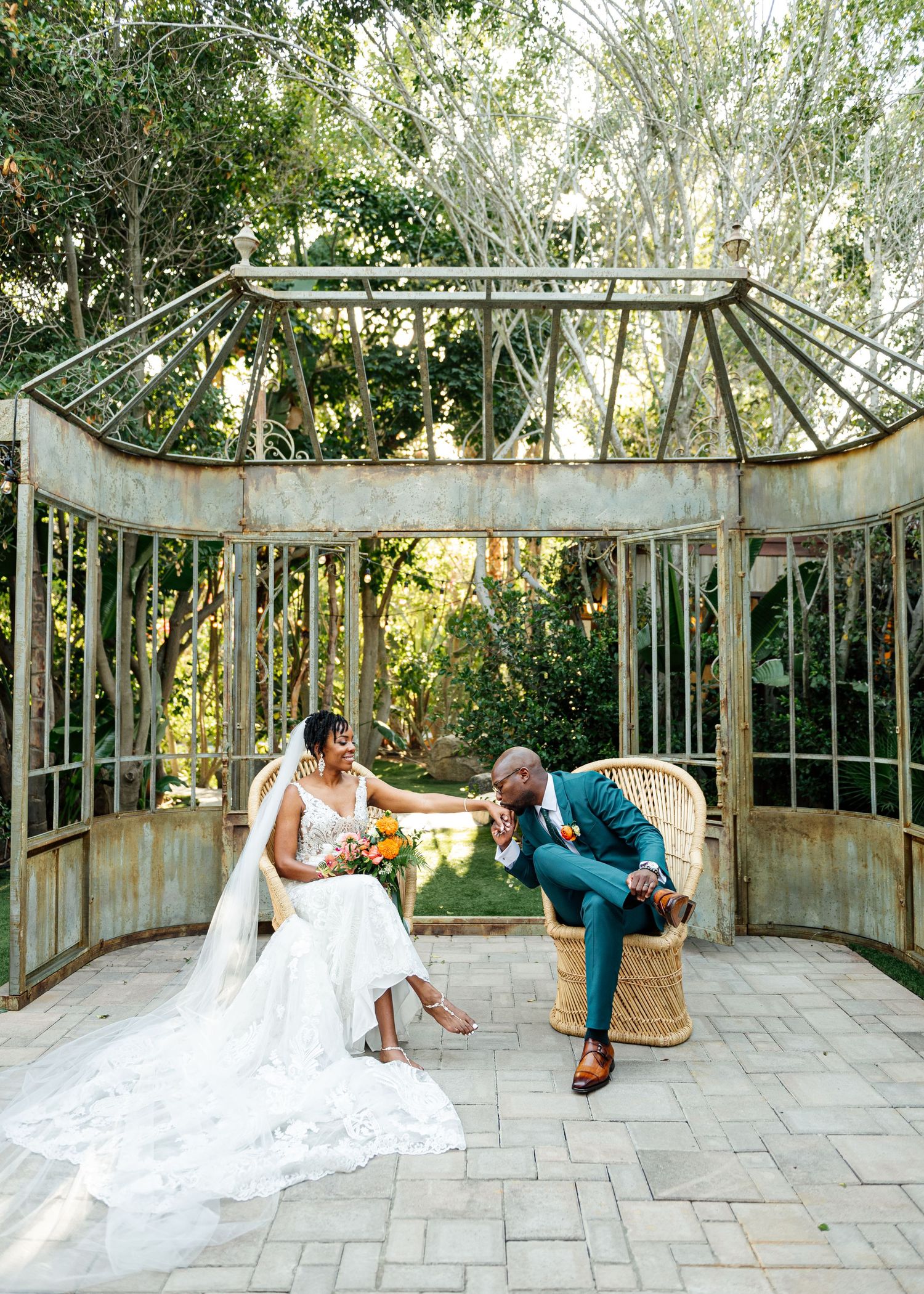 A romantic wedding moment captured in an elegant glass gazebo surrounded by lush greenery.