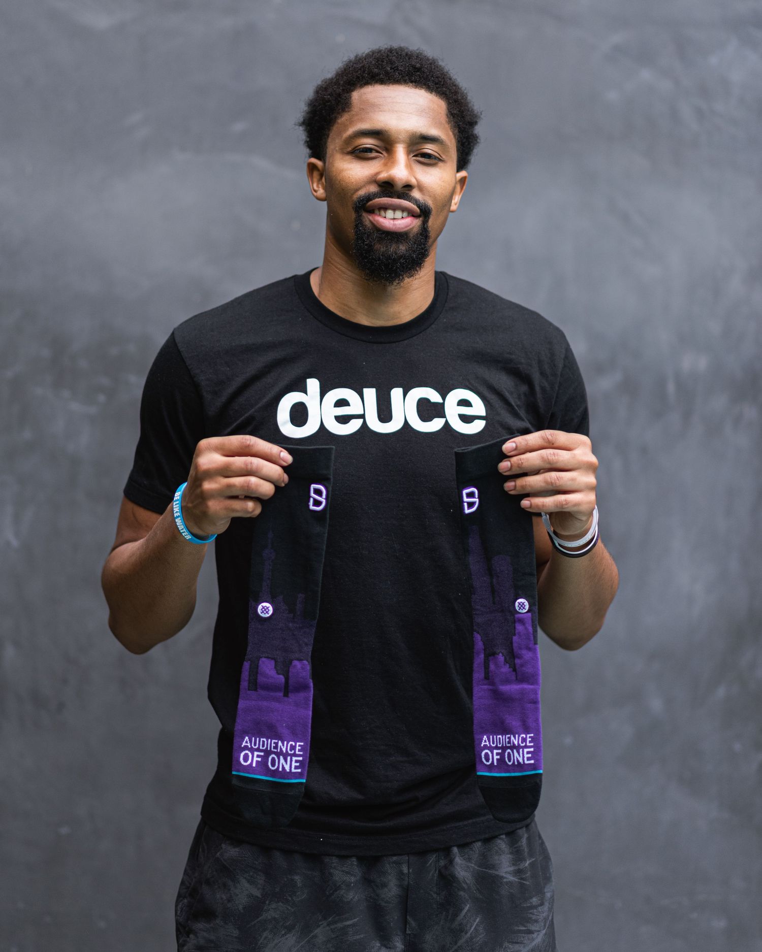 Person demonstrating product packaging with purple accents against dark background.