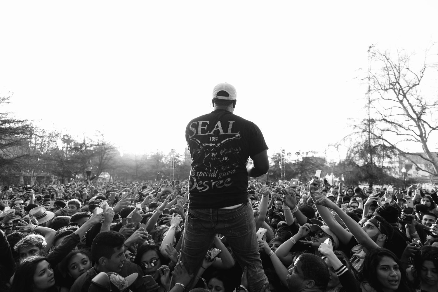 Crowd surfing scene at an outdoor concert with fans holding up a performer.