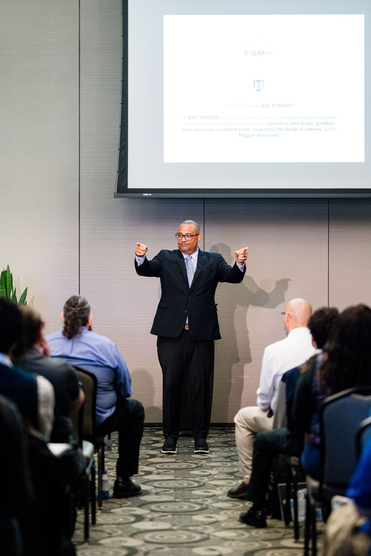 Professional presentation in a conference room with projection screen and seated audience.
