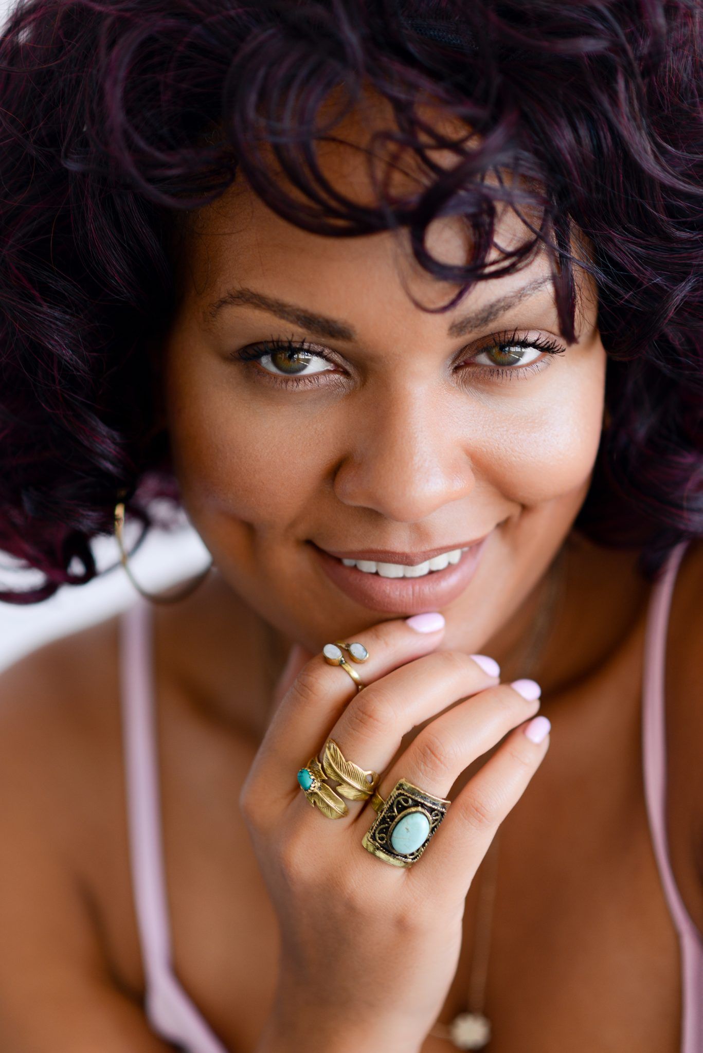 Close up portraits showing jewelry and natural curly hair against warm background.