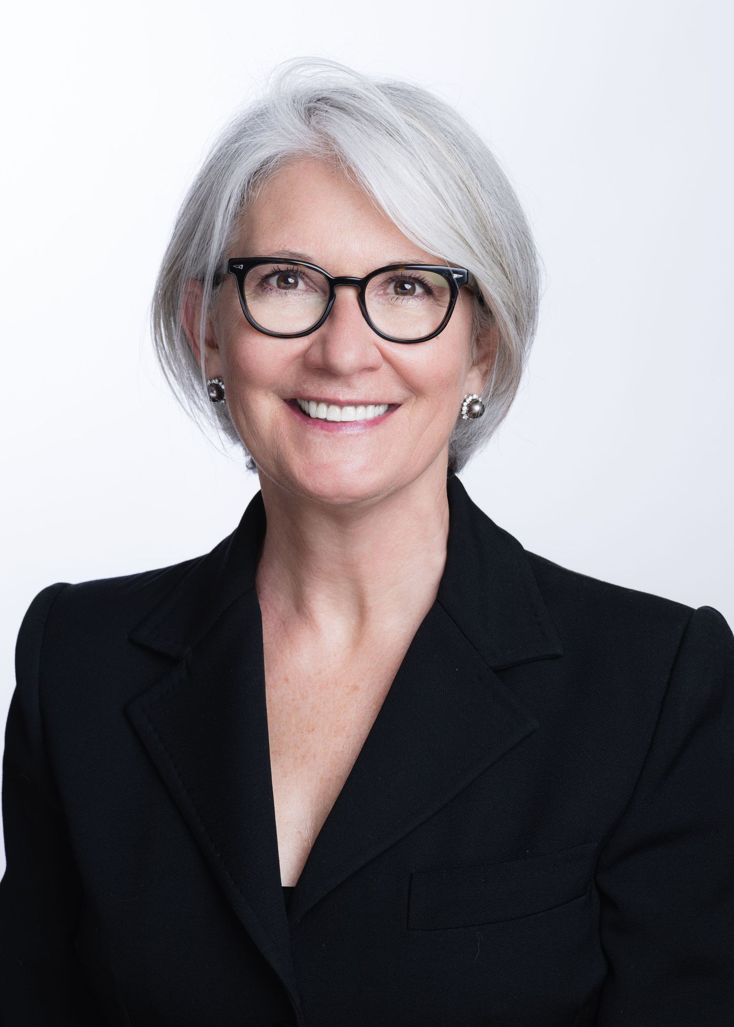 Professional headshots of person in black blazer and glasses against white background.
