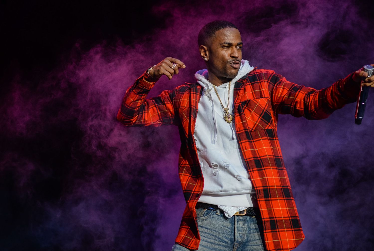 Energetic stage performance with purple smoke effects and dramatic lighting.