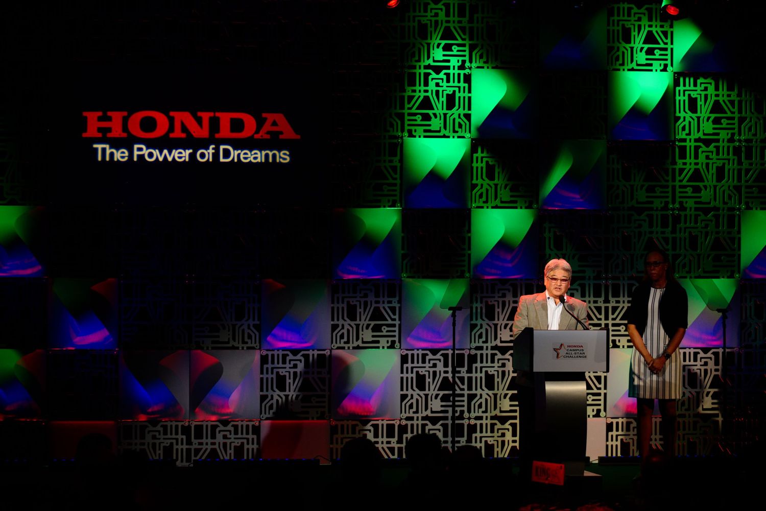 Honda stage setup with green and red lighting effects and cityscape backdrop.