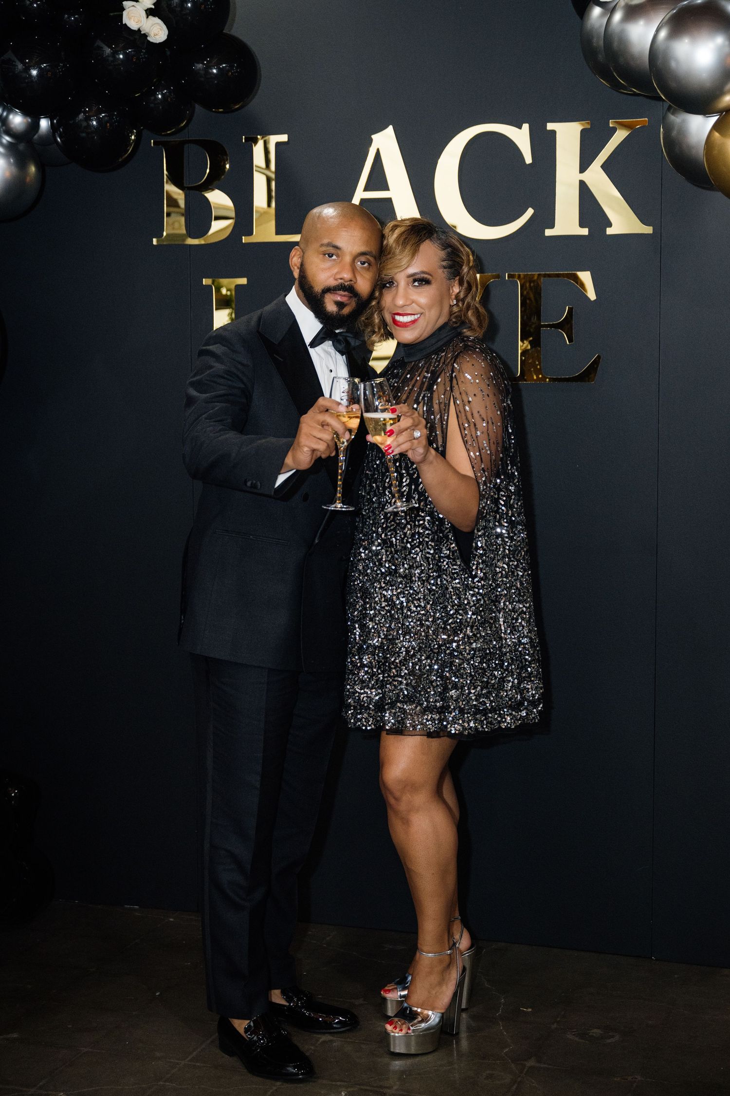 Formal event attendees in black attire pose together at an upscale venue.