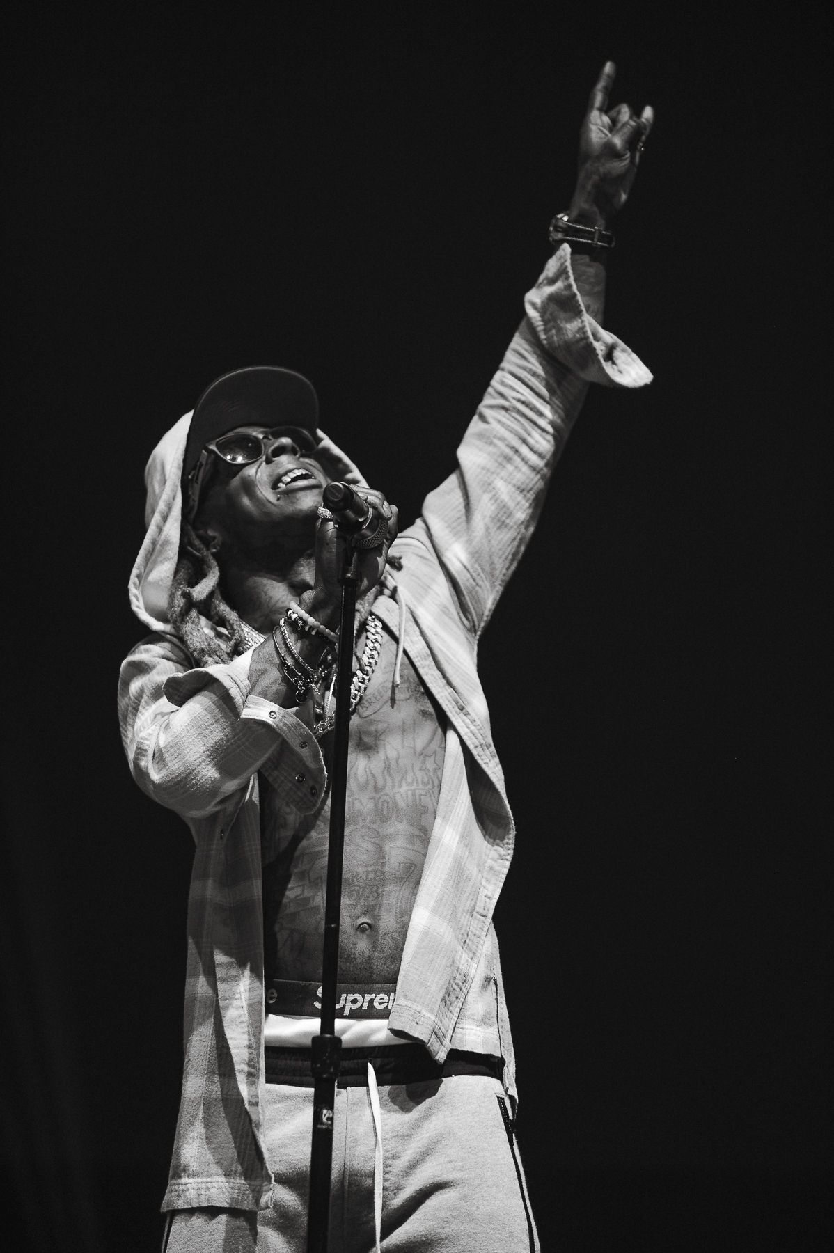 Black and white photo of performer in light colored outfit raising arm triumphantly on stage.