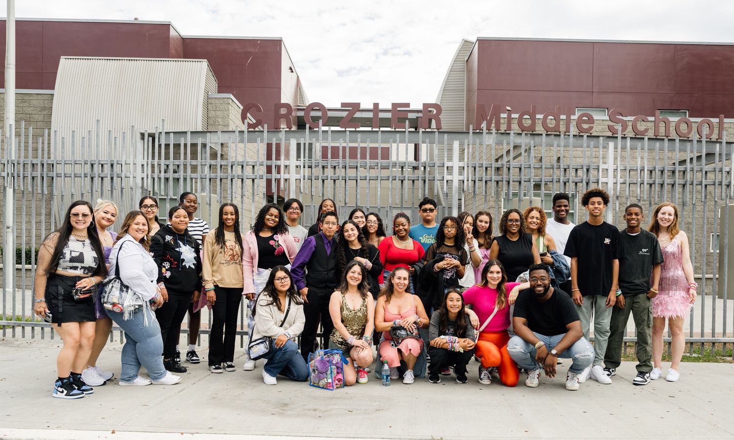 Large diverse group photo of people posing together outside a building.