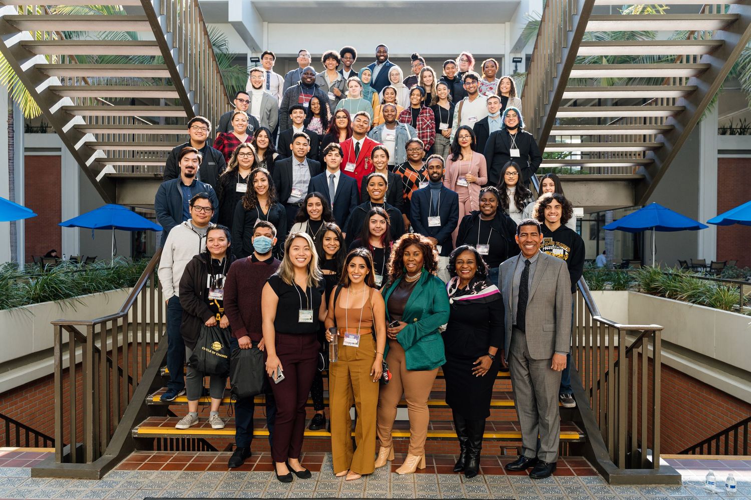 Large group photo of diverse professionals posing together on modern office stairs.