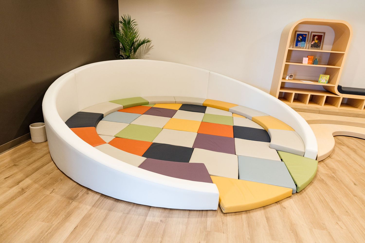 A curved modular seating area with colorful geometric cushions on a wooden floor.