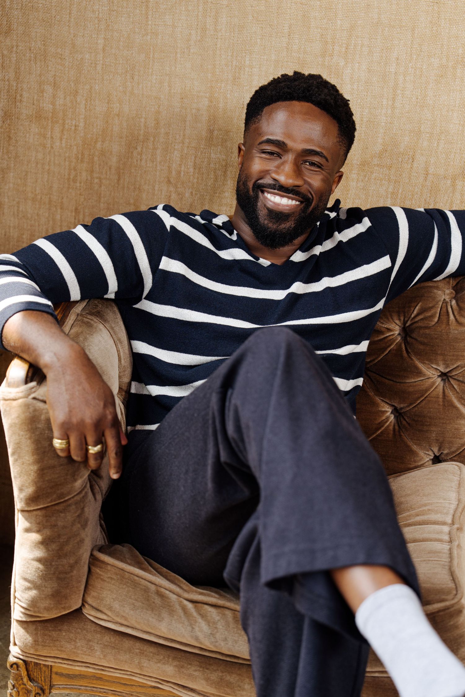 Person relaxing on brown leather couch wearing striped sweater.
