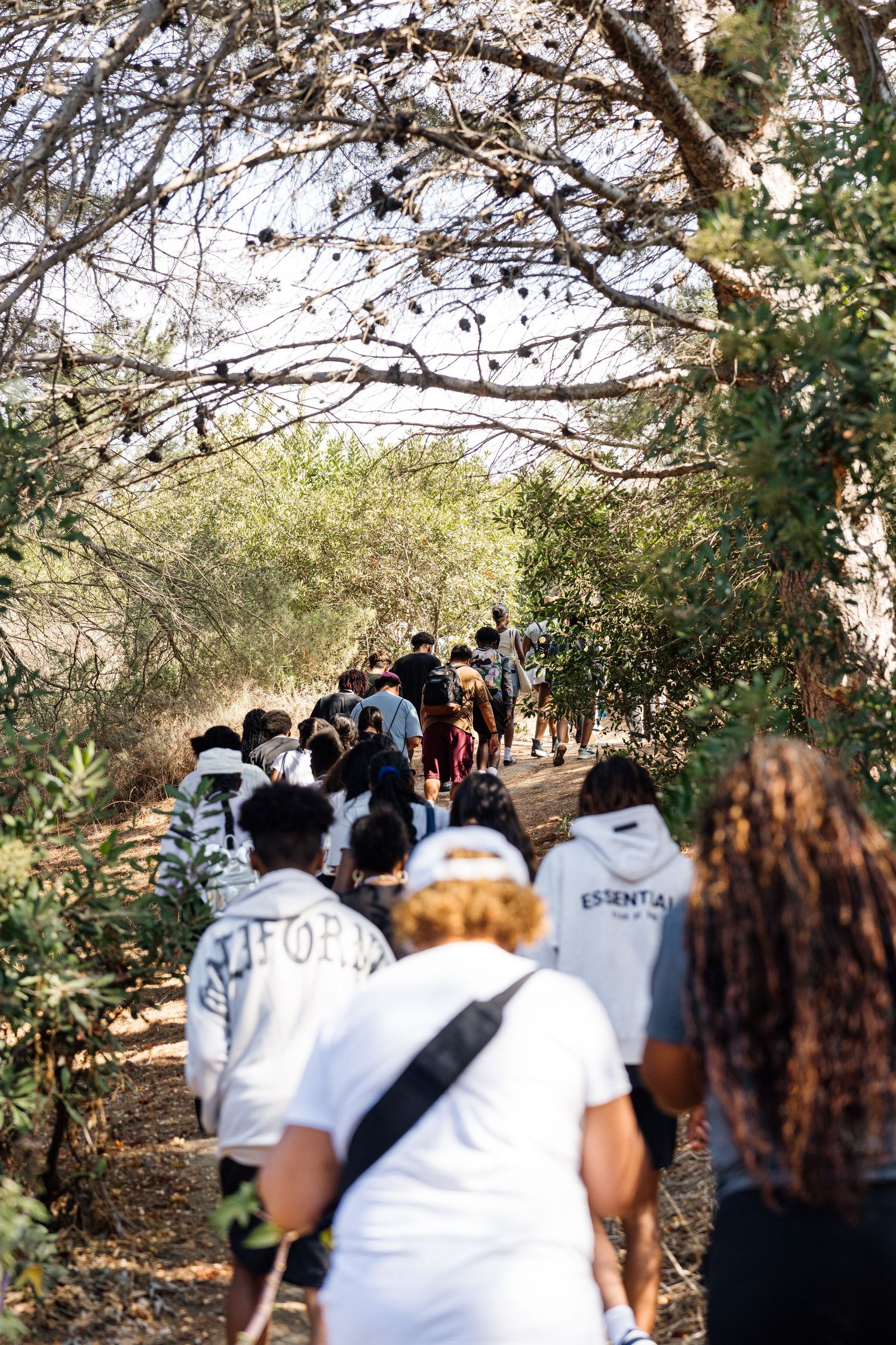 Group of students walking along tree-lined nature trail wearing USC apparel.