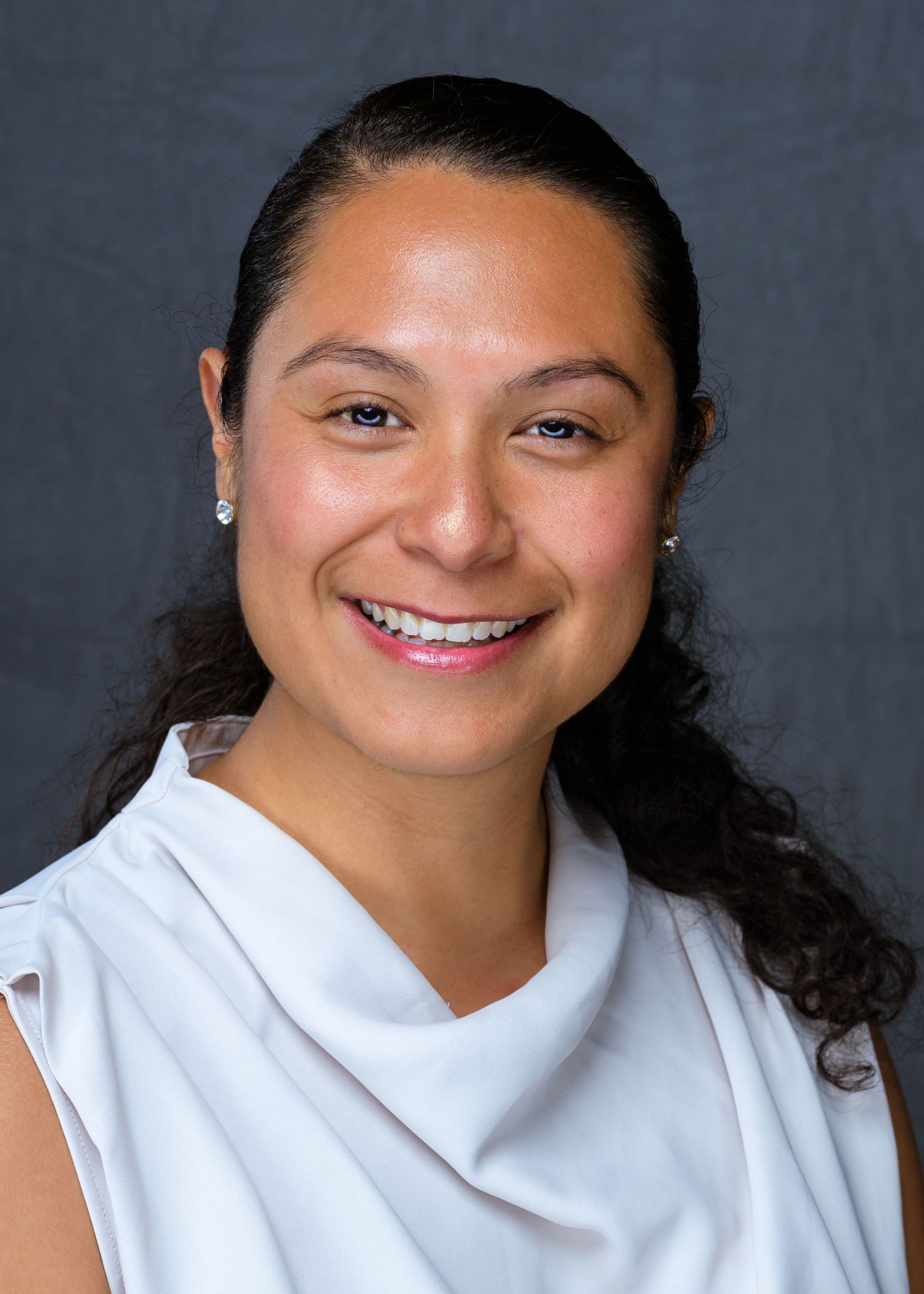 Professional headshots showing warm smiles in white top against dark background.