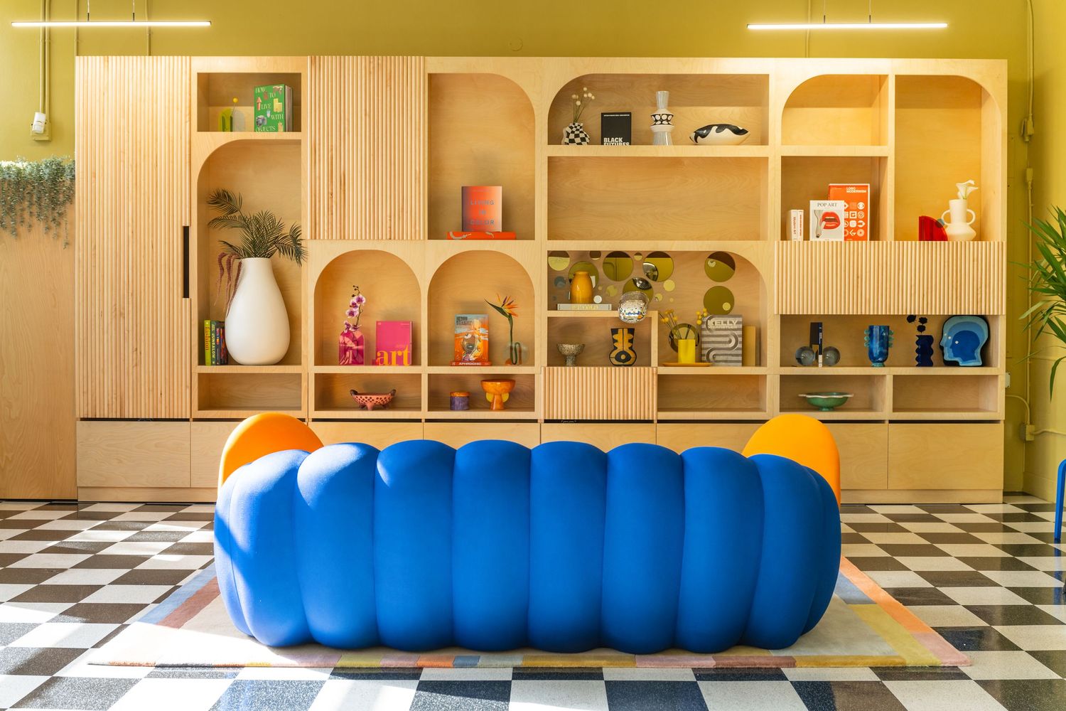 Modern interior with built-in shelving and blue furniture against checkered floor.