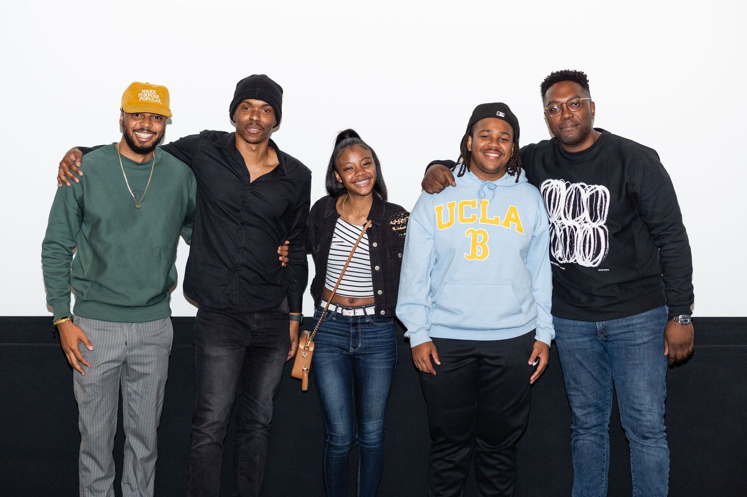 Five people standing together against a white background.
