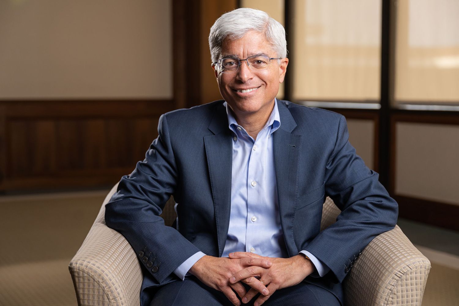 Corporate headshots showing warm expressions in business attire against neutral background.