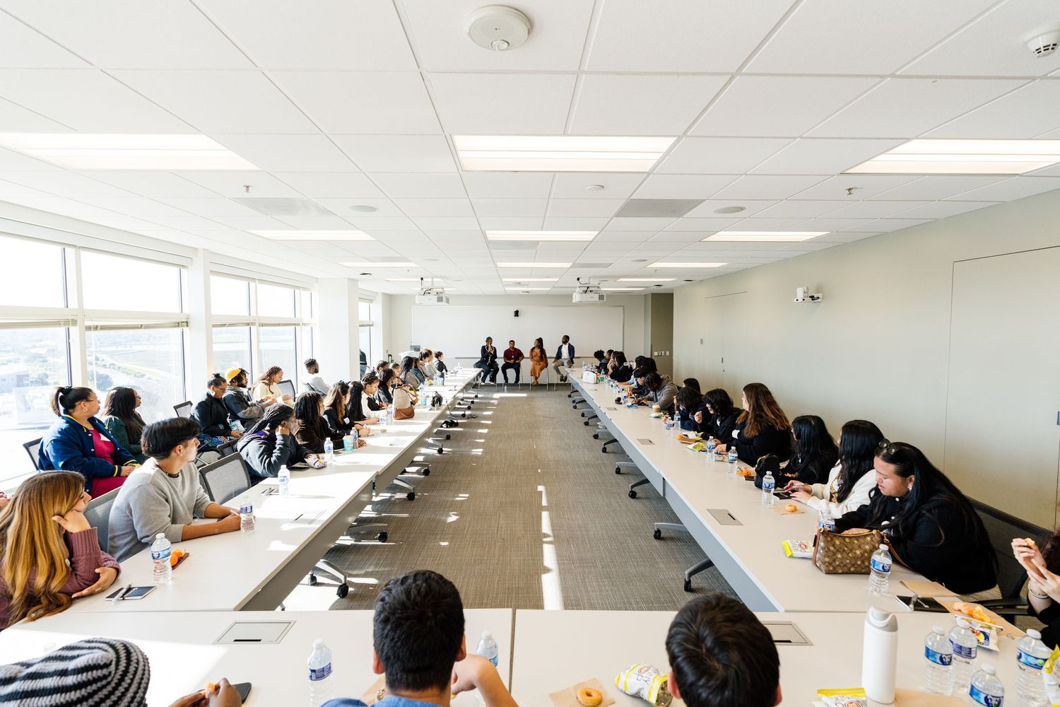 Long conference room filled with attendees seated at tables during a meeting.