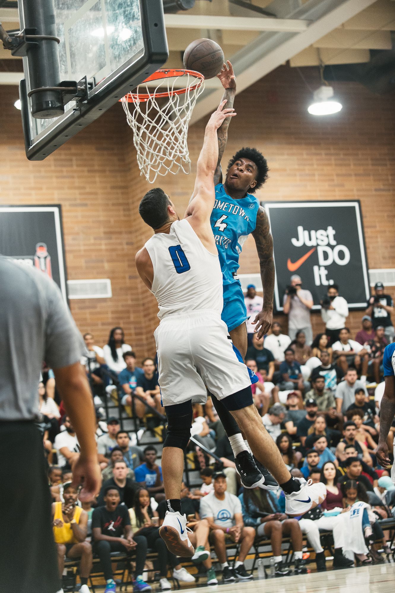 Basketball players competing in an indoor game with spectators watching from the sidelines.