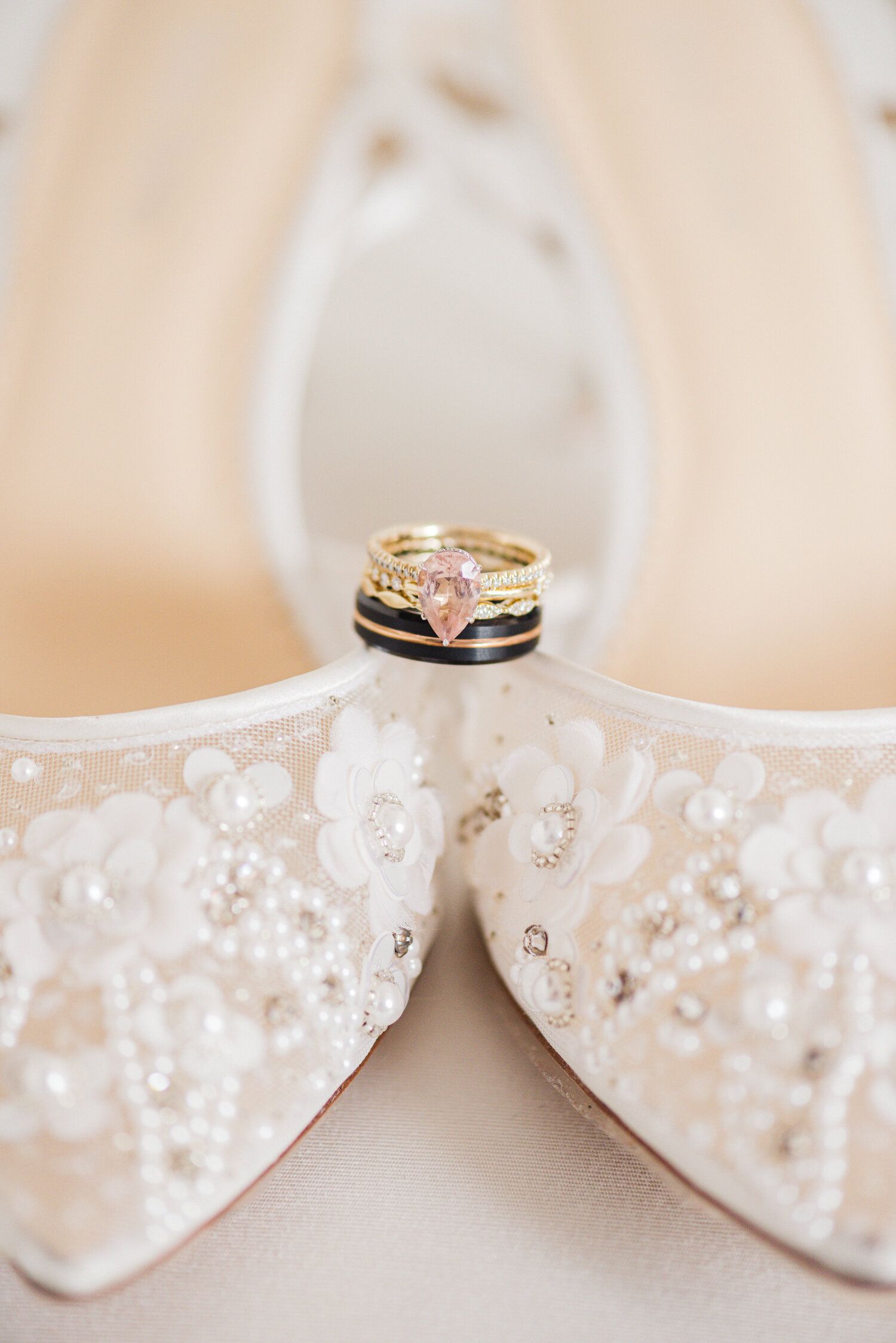Wedding rings displayed artistically on white lace bridal shoes.