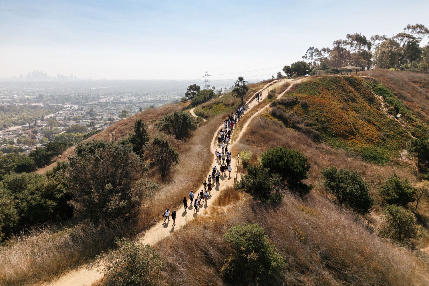 Scenic hiking trail winding along mountain ridge overlooking city views in the distance.