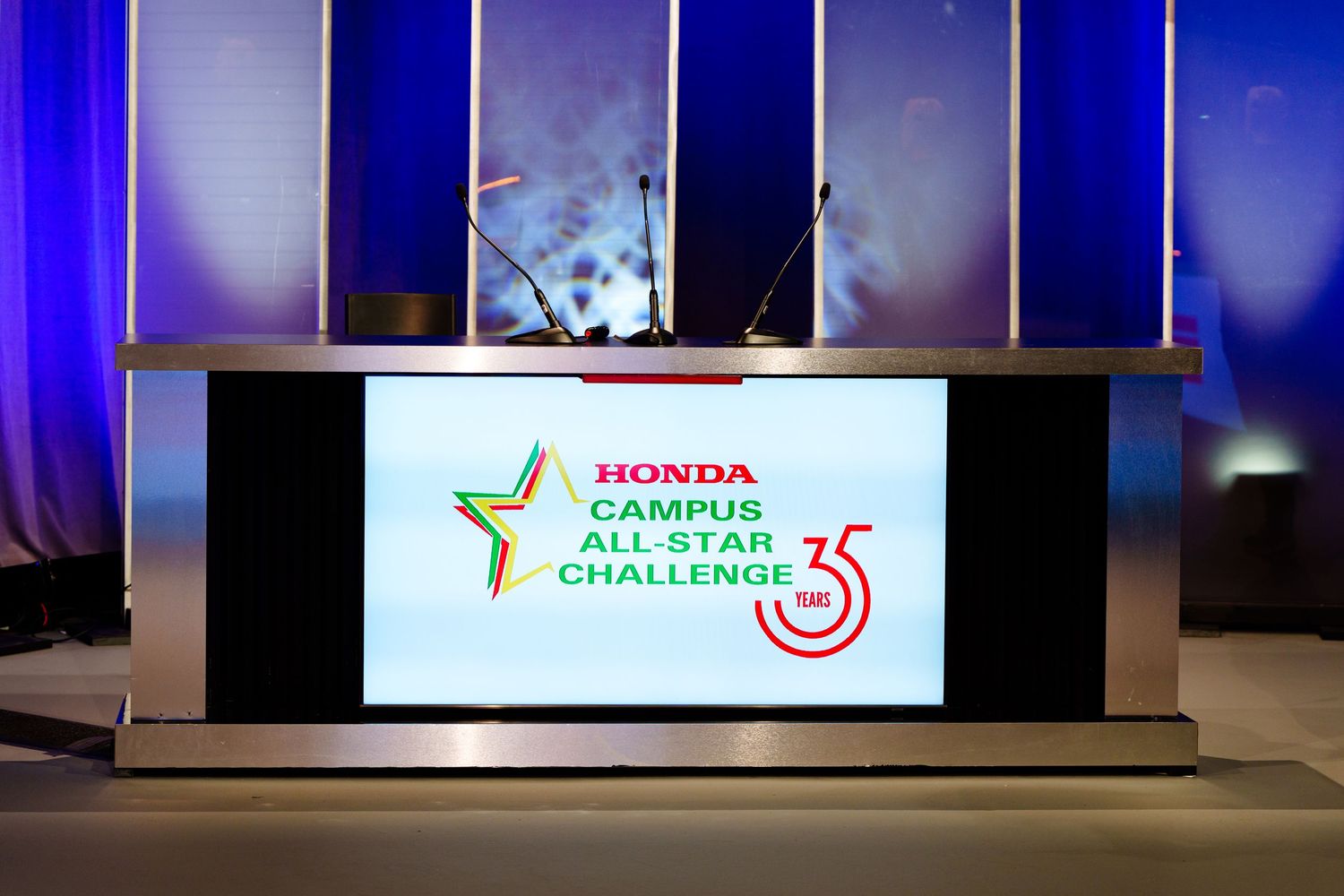 Wide view of stage with Honda Campus All-Star Challenge digital displays and blue lighting.